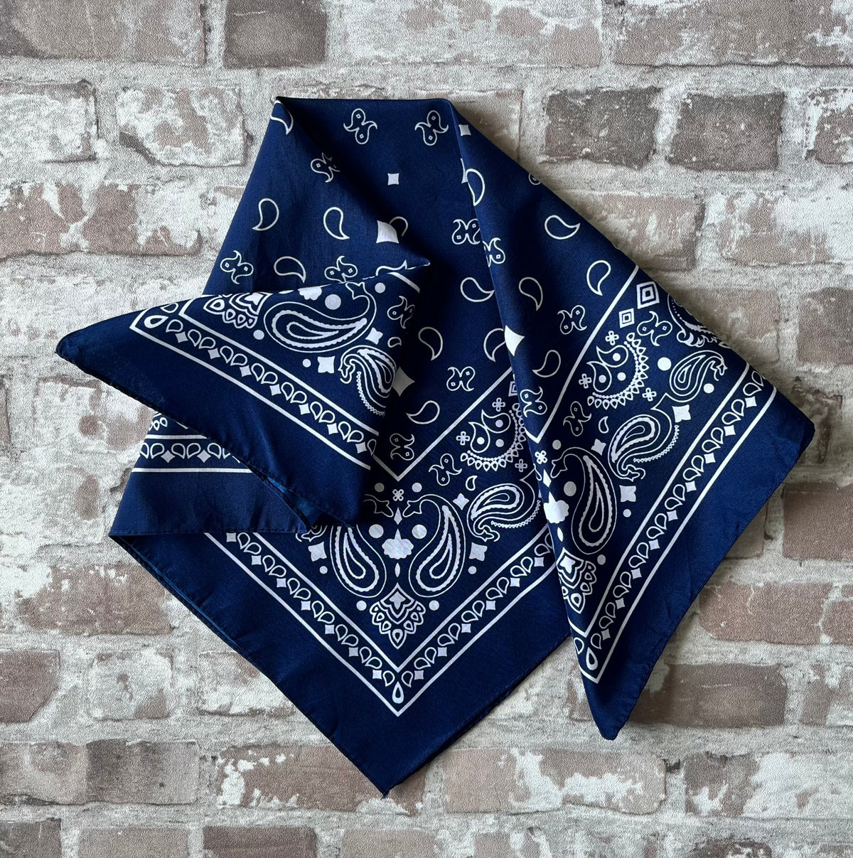 Bandana en coton vintage des années 90 couleur bleu marine au motif Paisley classique et bordure blanche, présenté plié à plat.