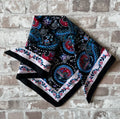 Bandana en coton vintage des années 90 au motif Paisley psychédélique turquoise et rouge sur fond noir, présenté plié à plat.