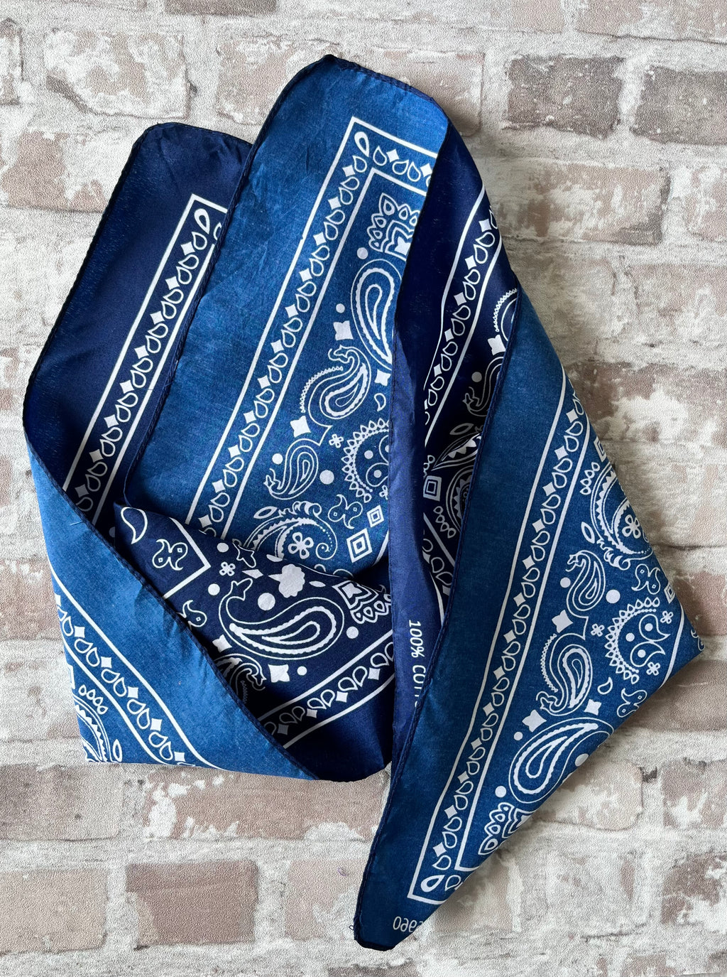 Bandana en coton vintage des années 90 couleur bleu marine au motif Paisley classique et bordure blanche, présenté plié à plat.