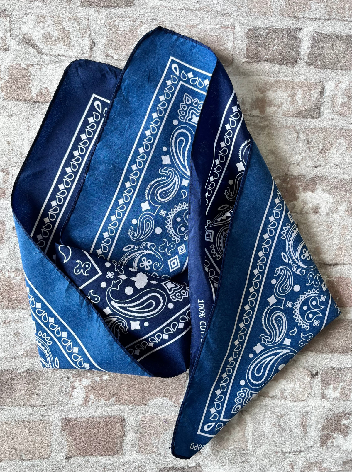 Bandana en coton vintage des années 90 couleur bleu marine au motif Paisley classique et bordure blanche, présenté plié à plat.