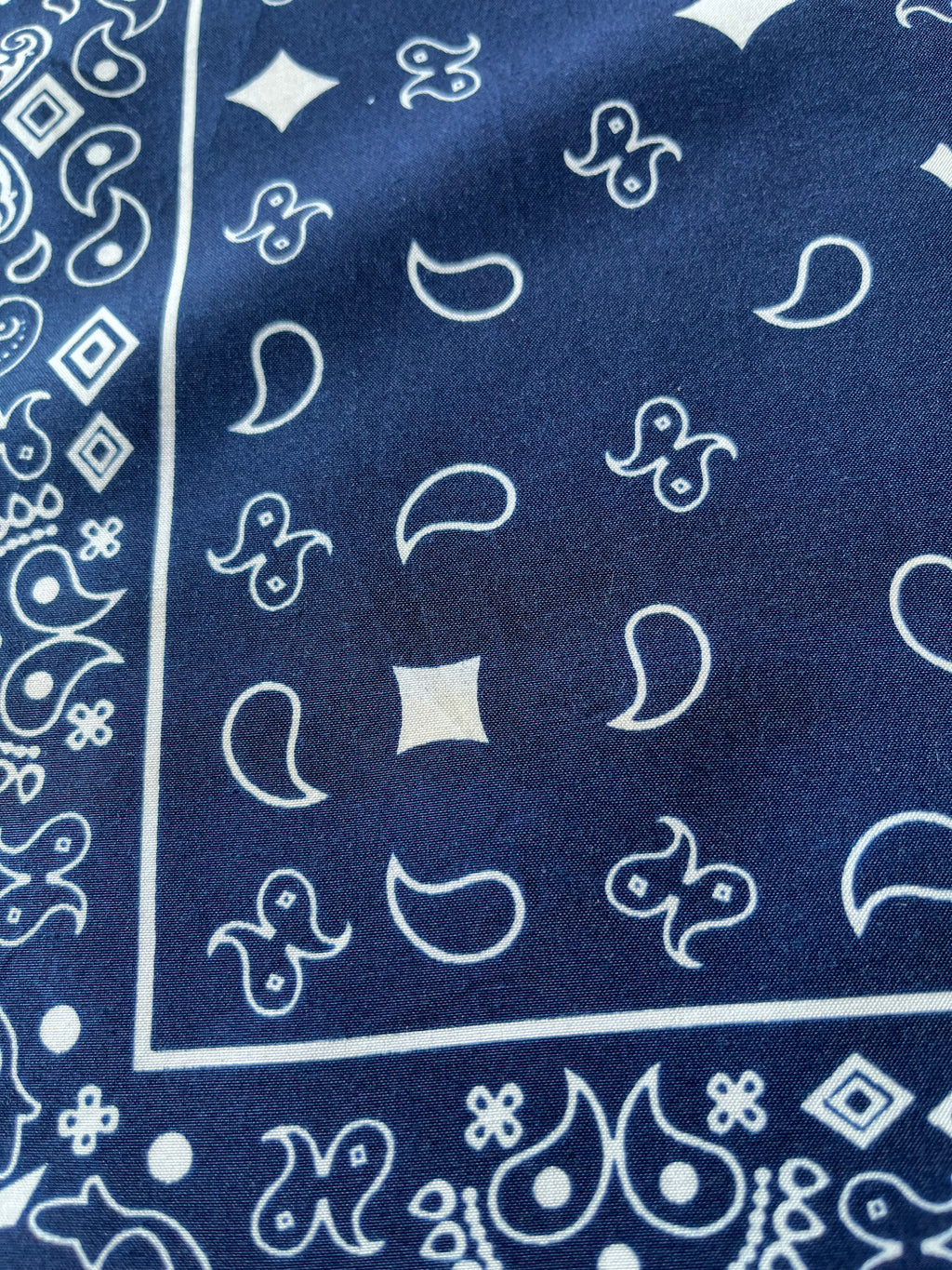 Bandana en coton vintage des années 90 couleur bleu marine au motif Paisley classique et bordure blanche, présenté à plat / Focus tache discrète