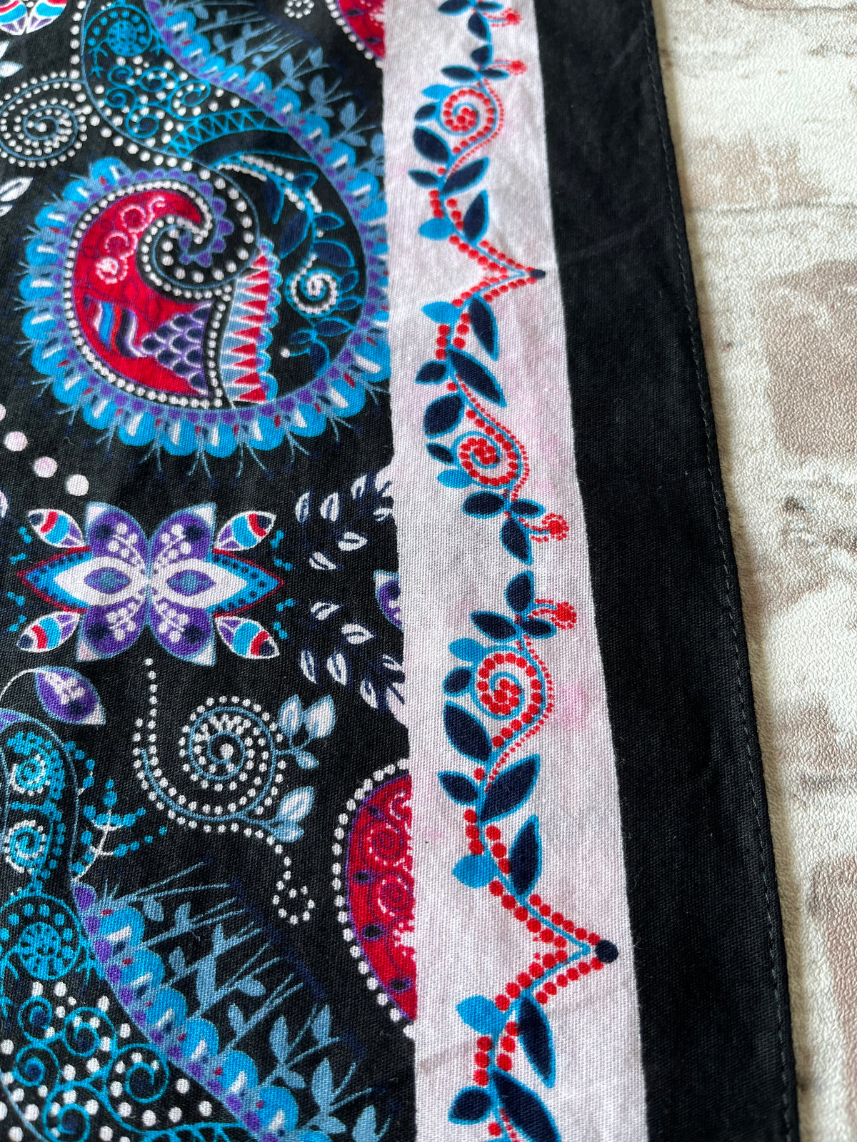 Bandana en coton vintage des années 90 au motif Paisley psychédélique turquoise et rouge sur fond noir, présenté plié à plat / détails décoloration