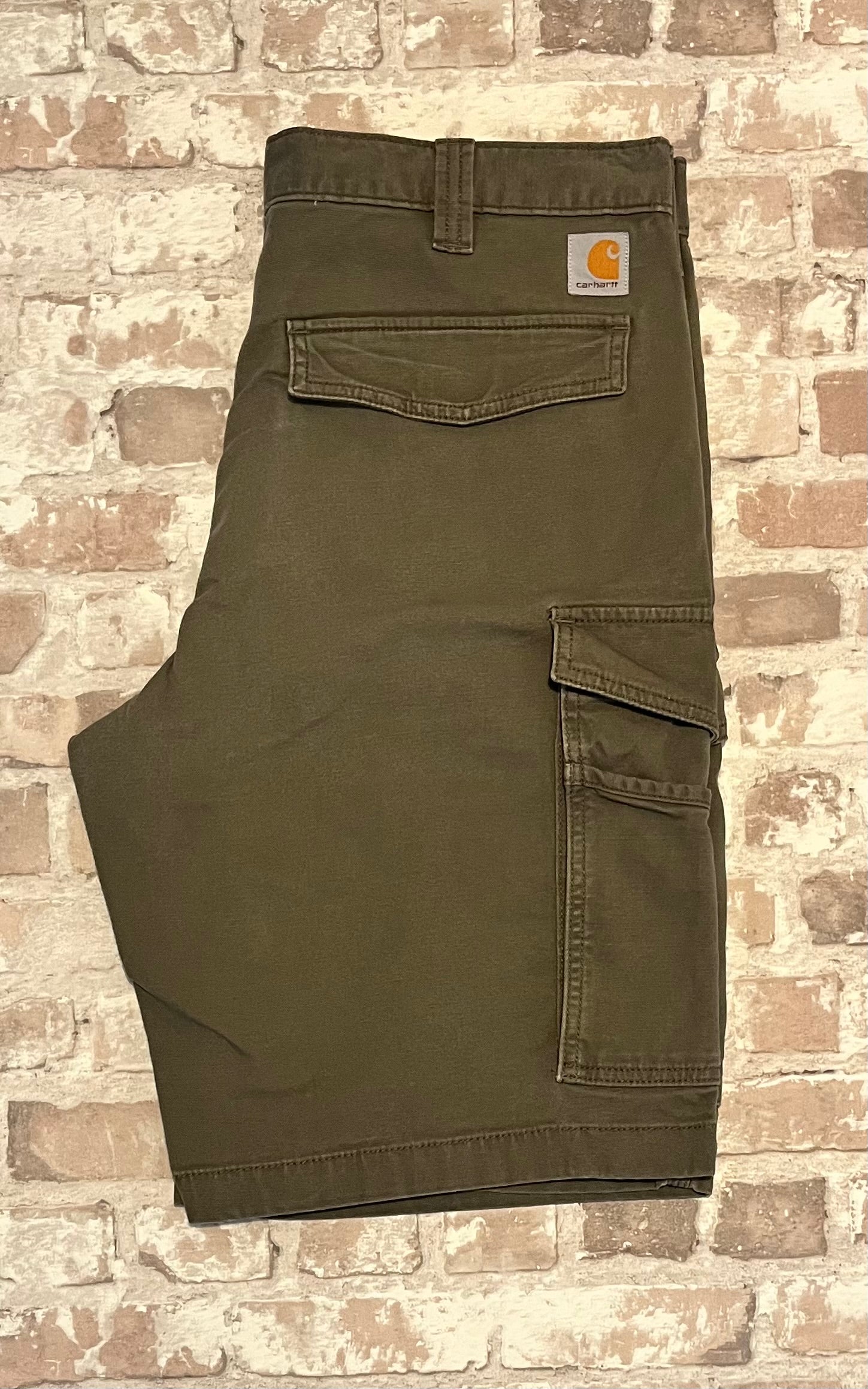 Short cargo de travail vert kaki Carhartt Tech Utility en toile canvas stretch, présenté à plat, plié, de dos.