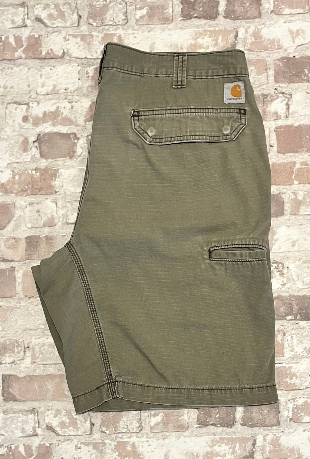 Short cargo gris-beige Carhartt Ripstop plié à plat, mettant en avant le tissage quadrillé et la patine d'usage sur la poche.