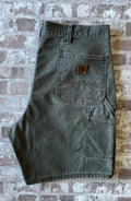 Plan sur la poche arrière droite avant restauration et le patch logo Carhartt en cuir véritable patiné d'un short vintage.