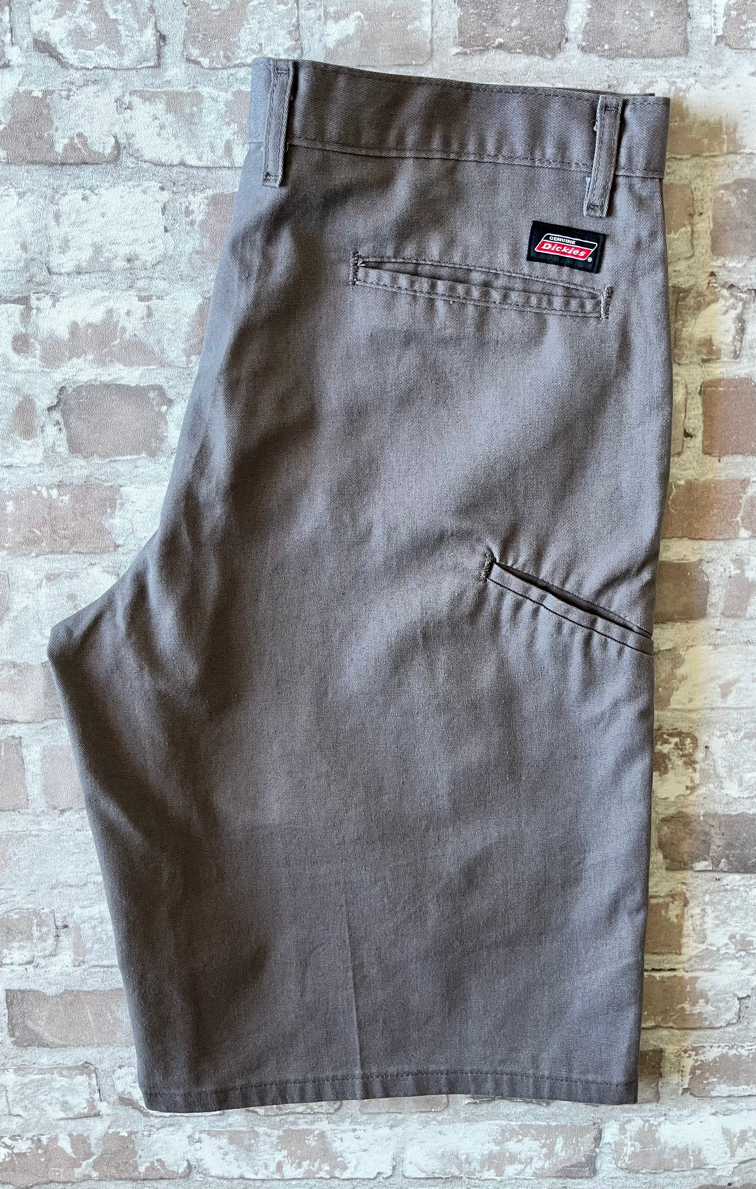 Short cargo asymétrique Dickies gris étain avec une seule poche latérale sur la jambe droite, présenté à plat.