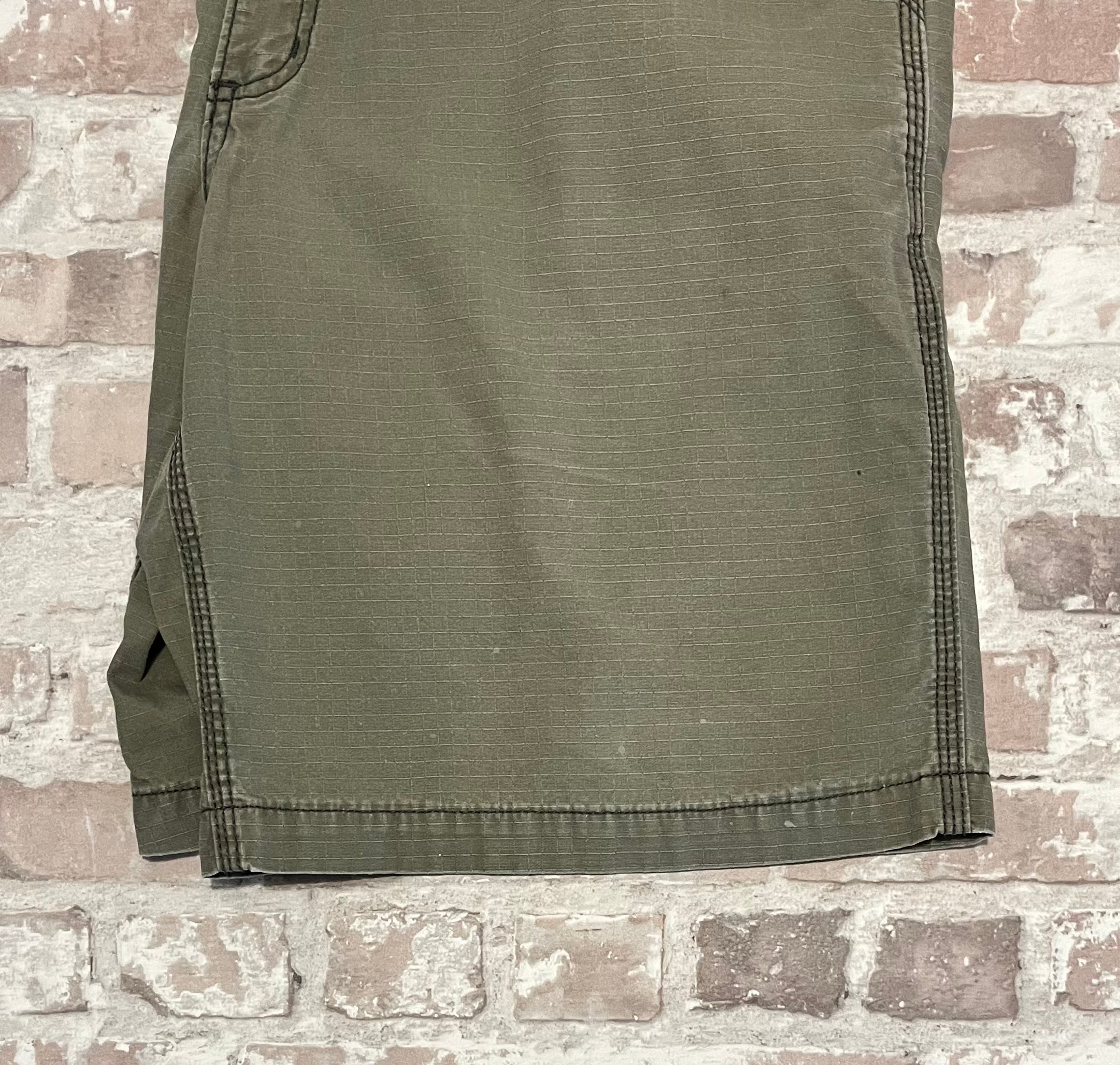 Gros plan sur de légers éclats de peinture et la patine d'usage sur la poche d'un short cargo Carhartt de seconde main.