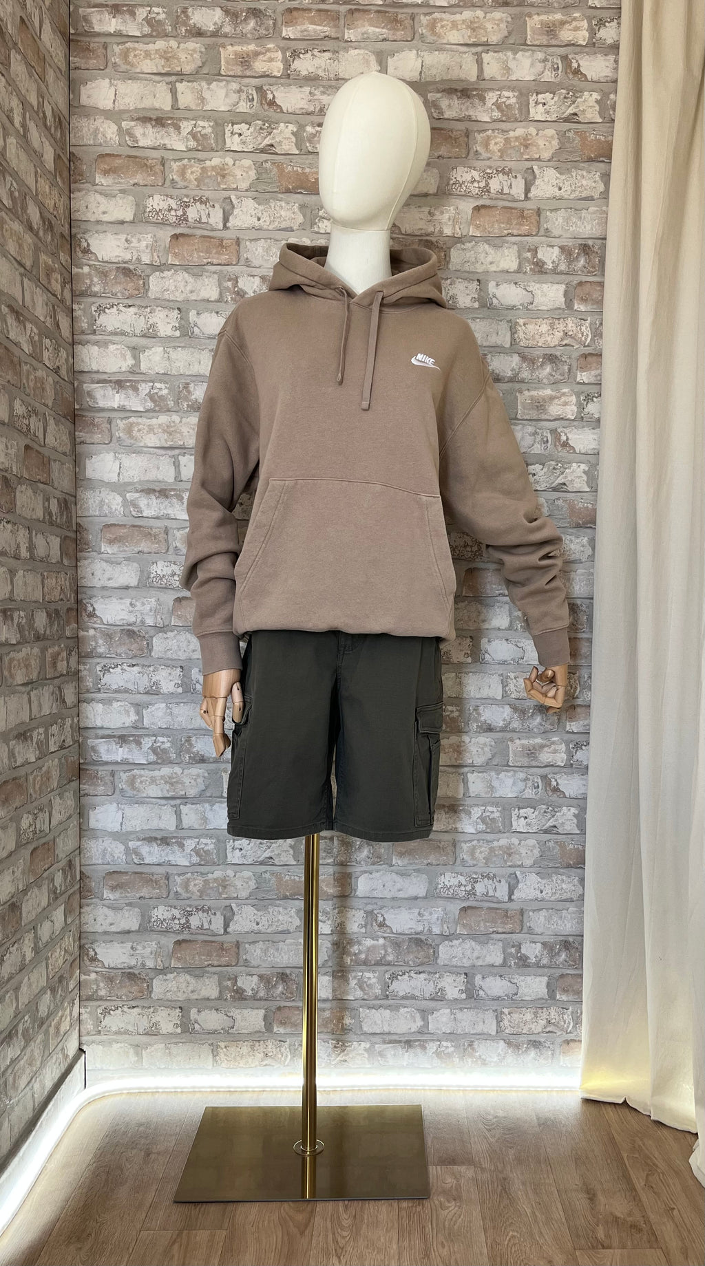 Hoodie Nike Sportswear beige sable avec logo brodé blanc porté avec un short bermuda cargo Carhartt Rugged Flex court.