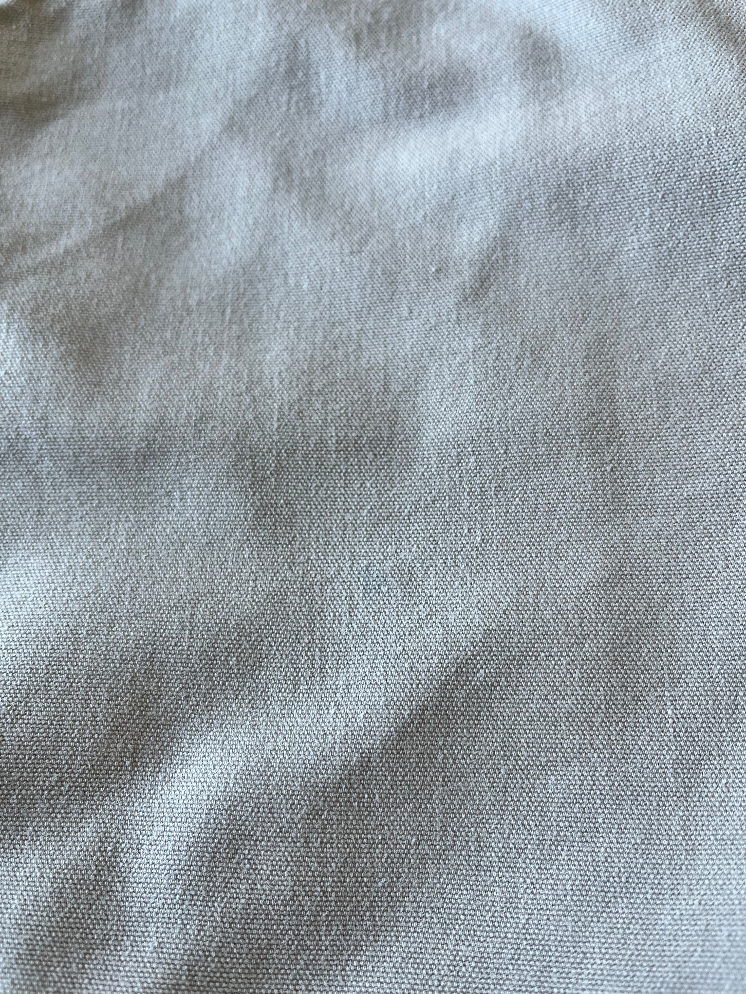 Gros plan sur la toile beige d'un short de menuisier Carhartt présentant une légère tache bleue sur la jambe.