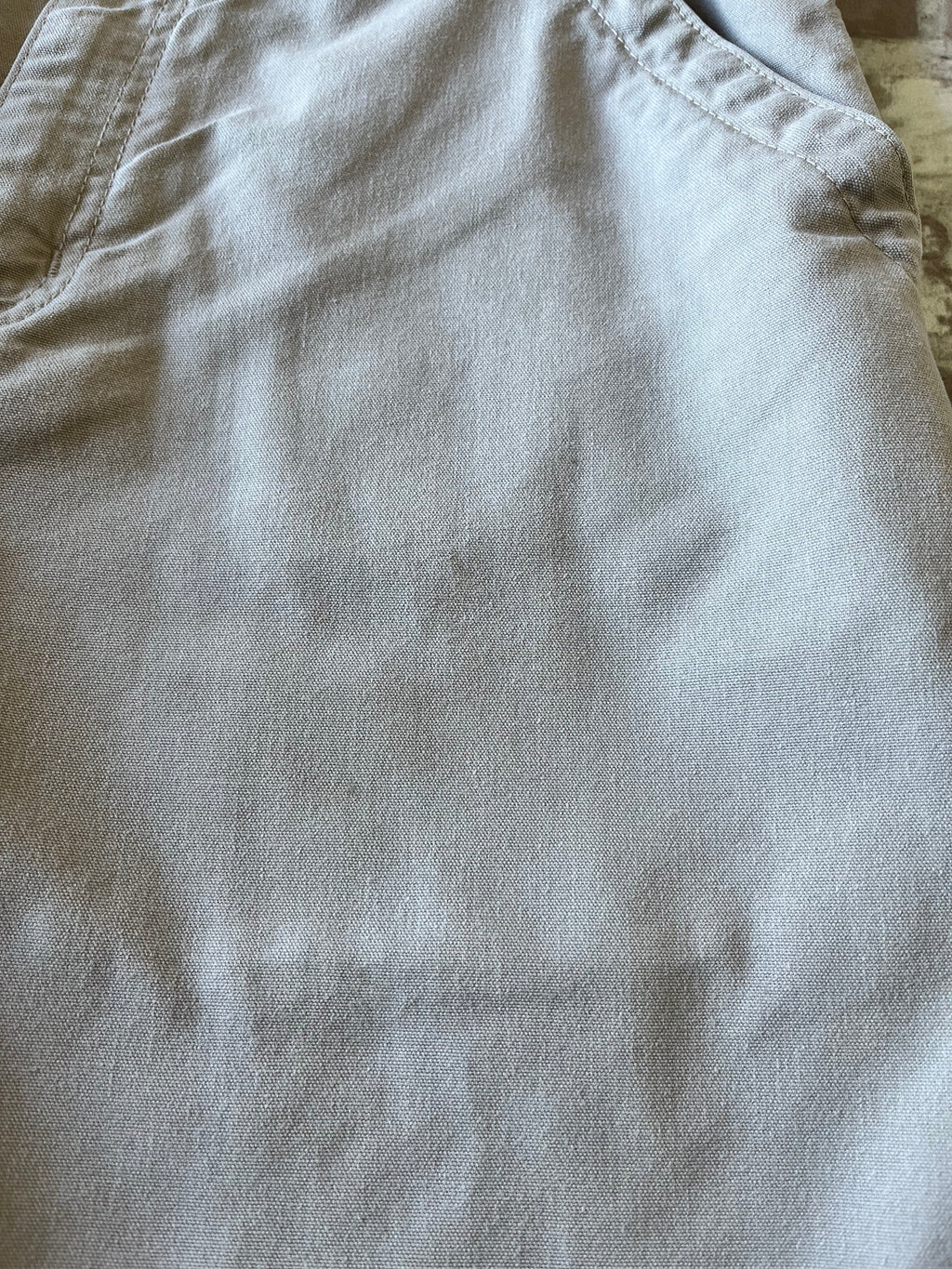 Gros plan sur la toile beige d'un short de menuisier Carhartt présentant une légère tache bleue sur la jambe.