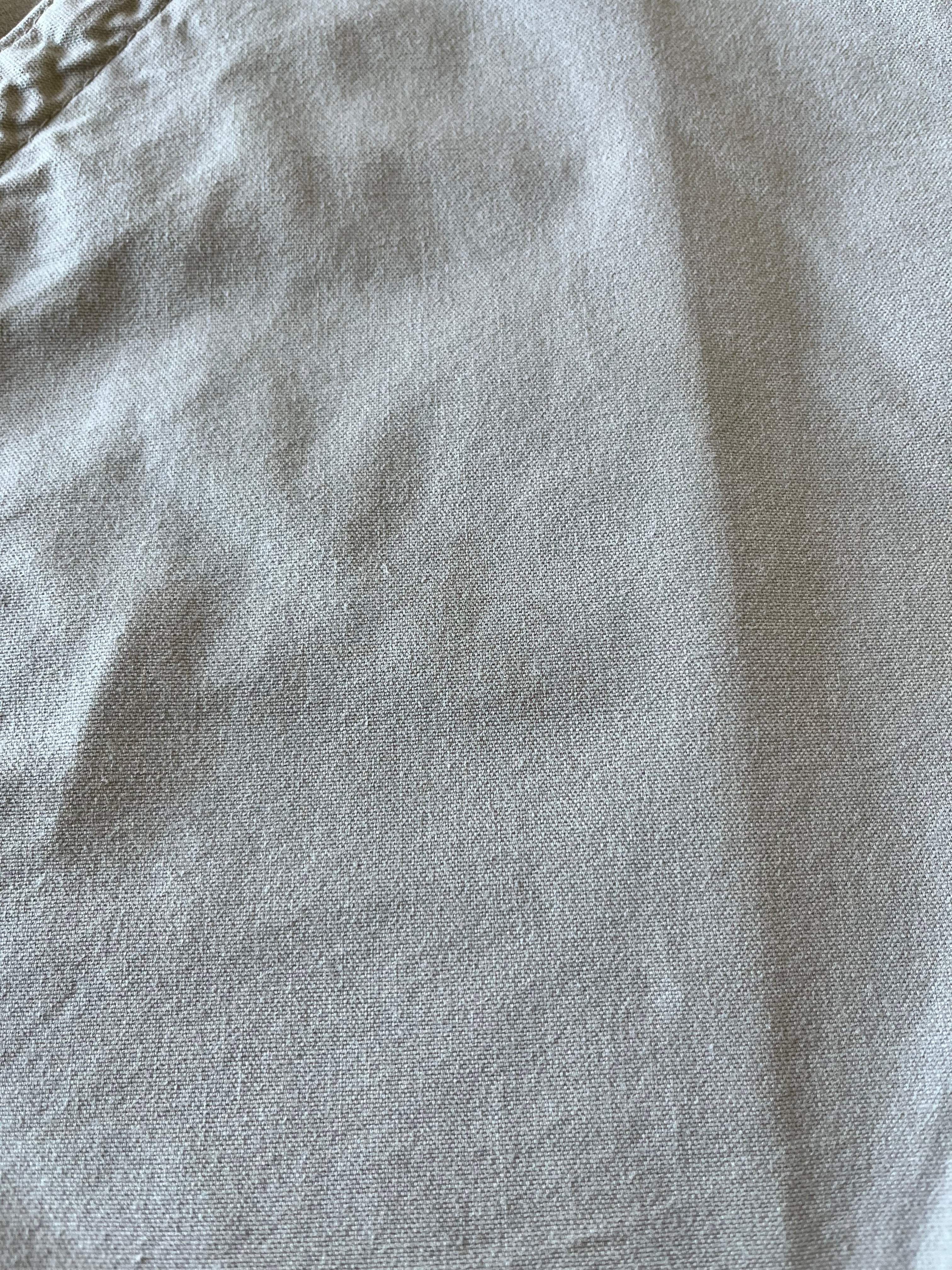 Gros plan sur des micro-taches de surface très discrètes situées sur la toile de coton beige d'un short Carhartt.