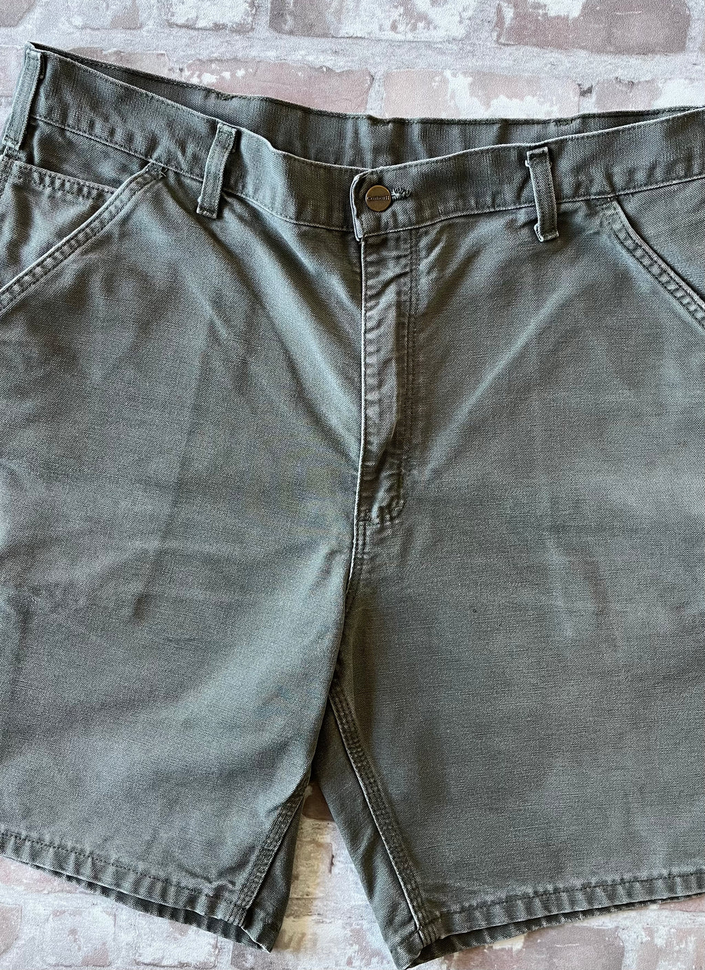Bermuda de travail vert Moss Carhartt B25 à plat, mettant en valeur la toile en coton canvas délavée 