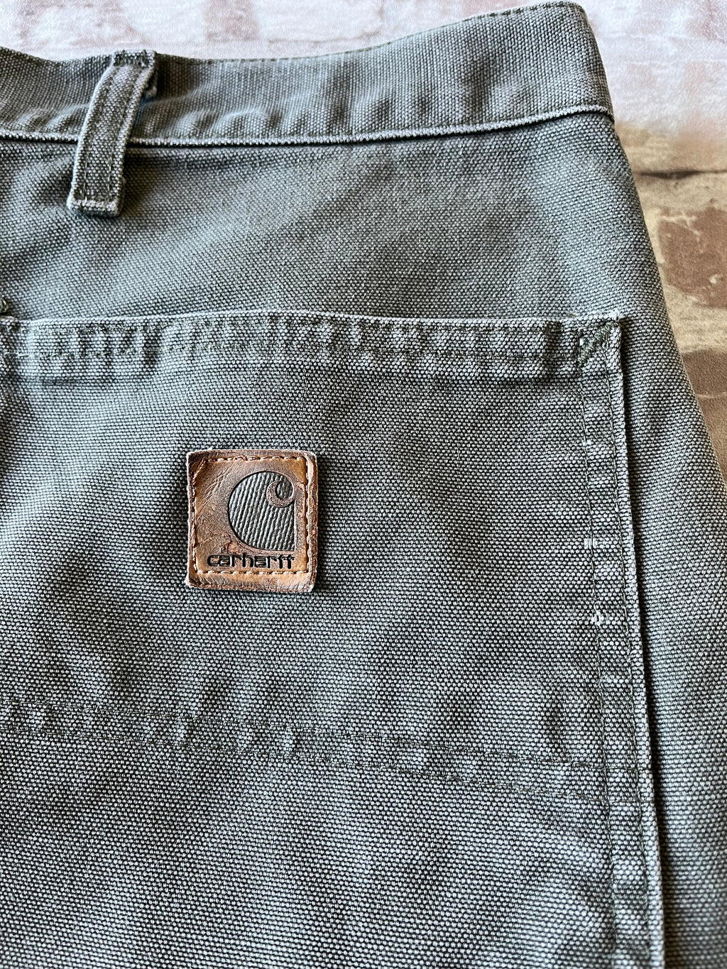 Gros plan sur le patch logo Carhartt en cuir véritable patiné d'un short vintage