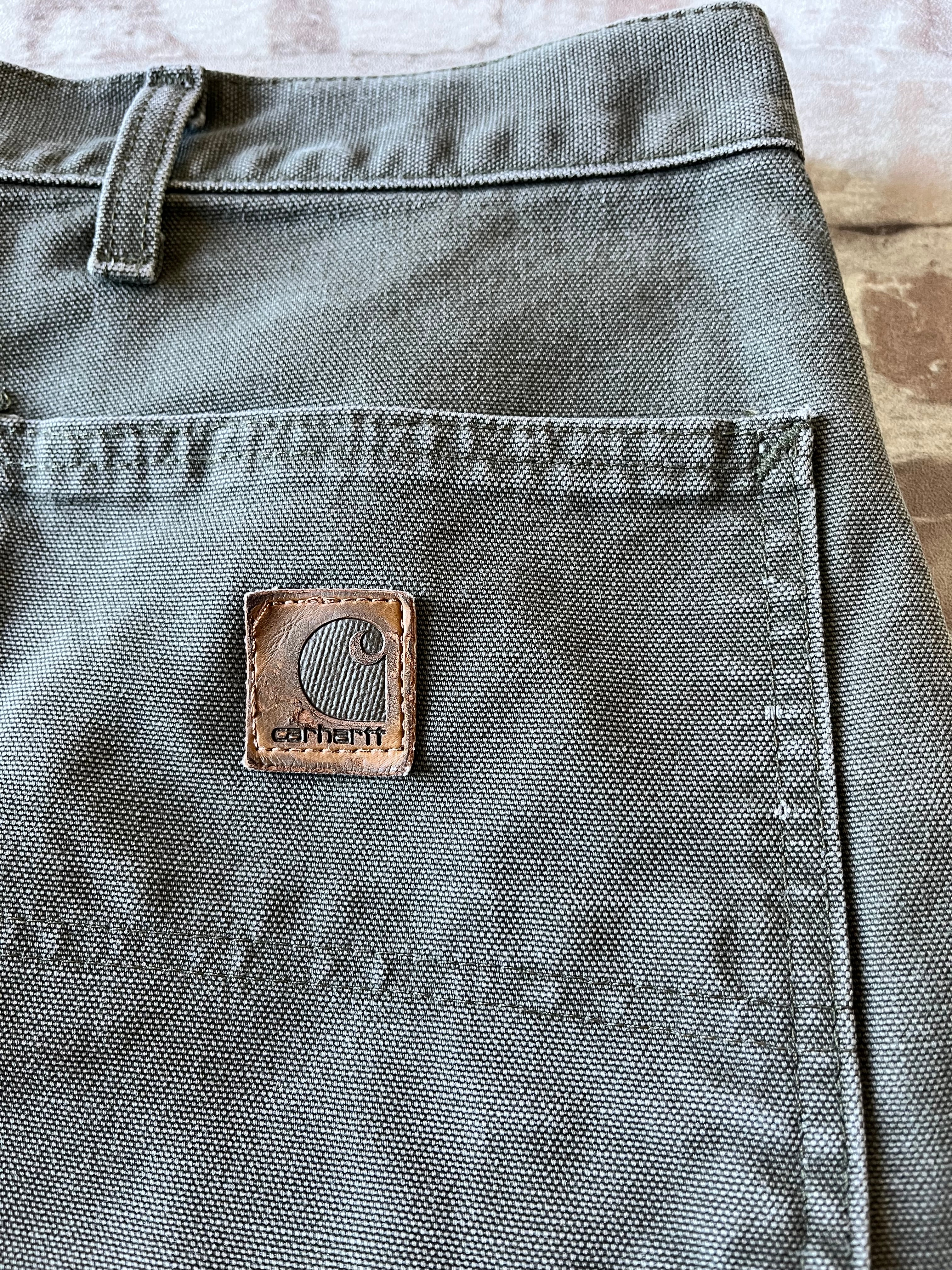 Gros plan sur le patch logo Carhartt en cuir véritable patiné d'un short vintage