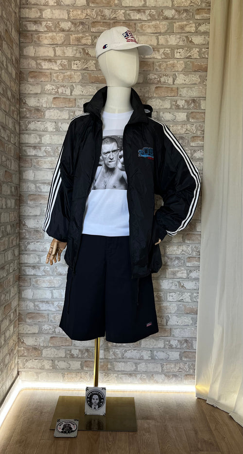 Bermuda Dickies , 13" Loose Fit Noir  porté sur un mannequin de face avec t-shirt Grafitee La Haine , une Parka outdoor rétro noire et une casquette Champion Vintage, au sol des Patchs La Barbuda.