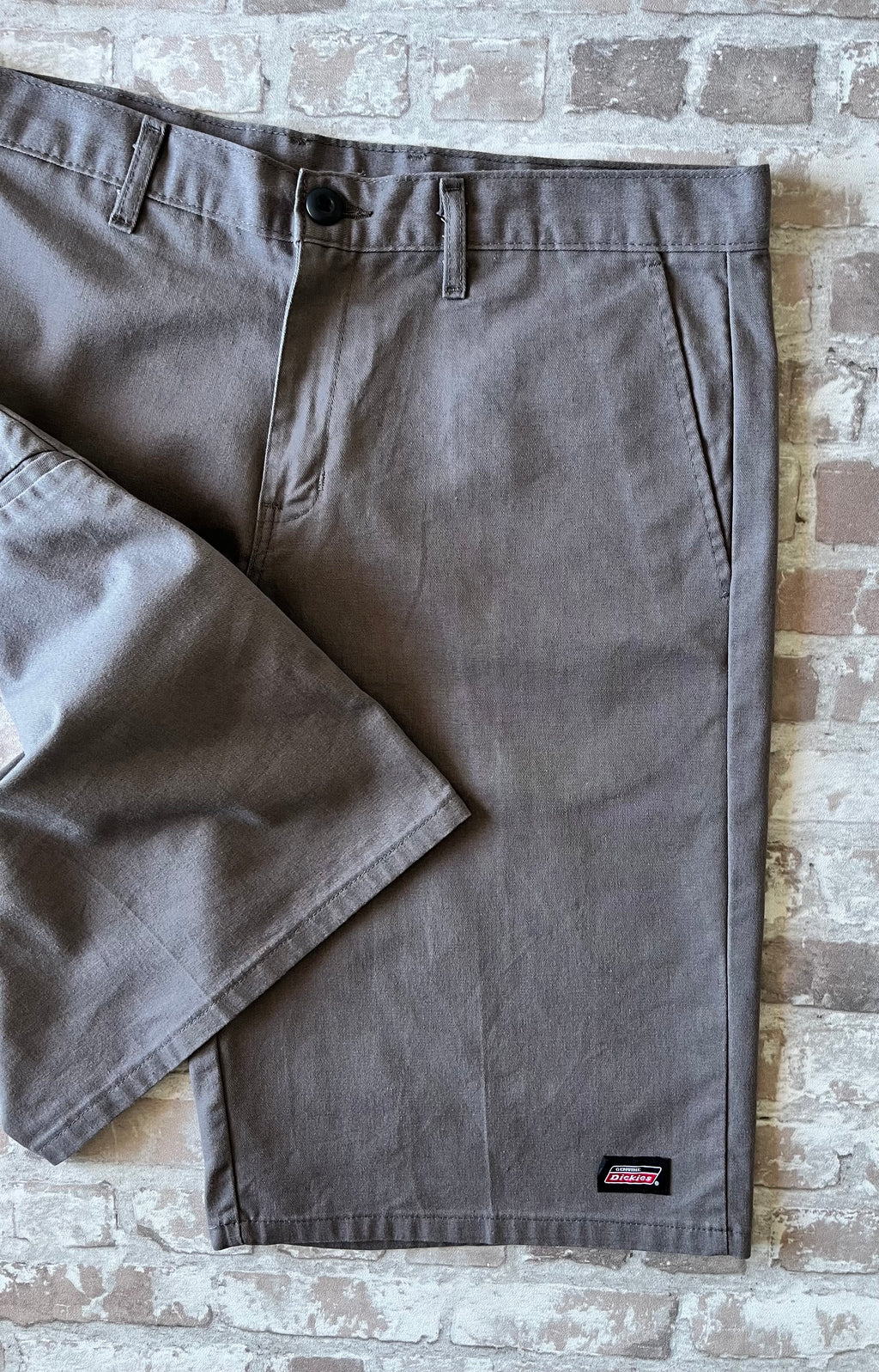 Short cargo asymétrique Dickies gris étain avec une seule poche latérale sur la jambe droite, présenté à plat.