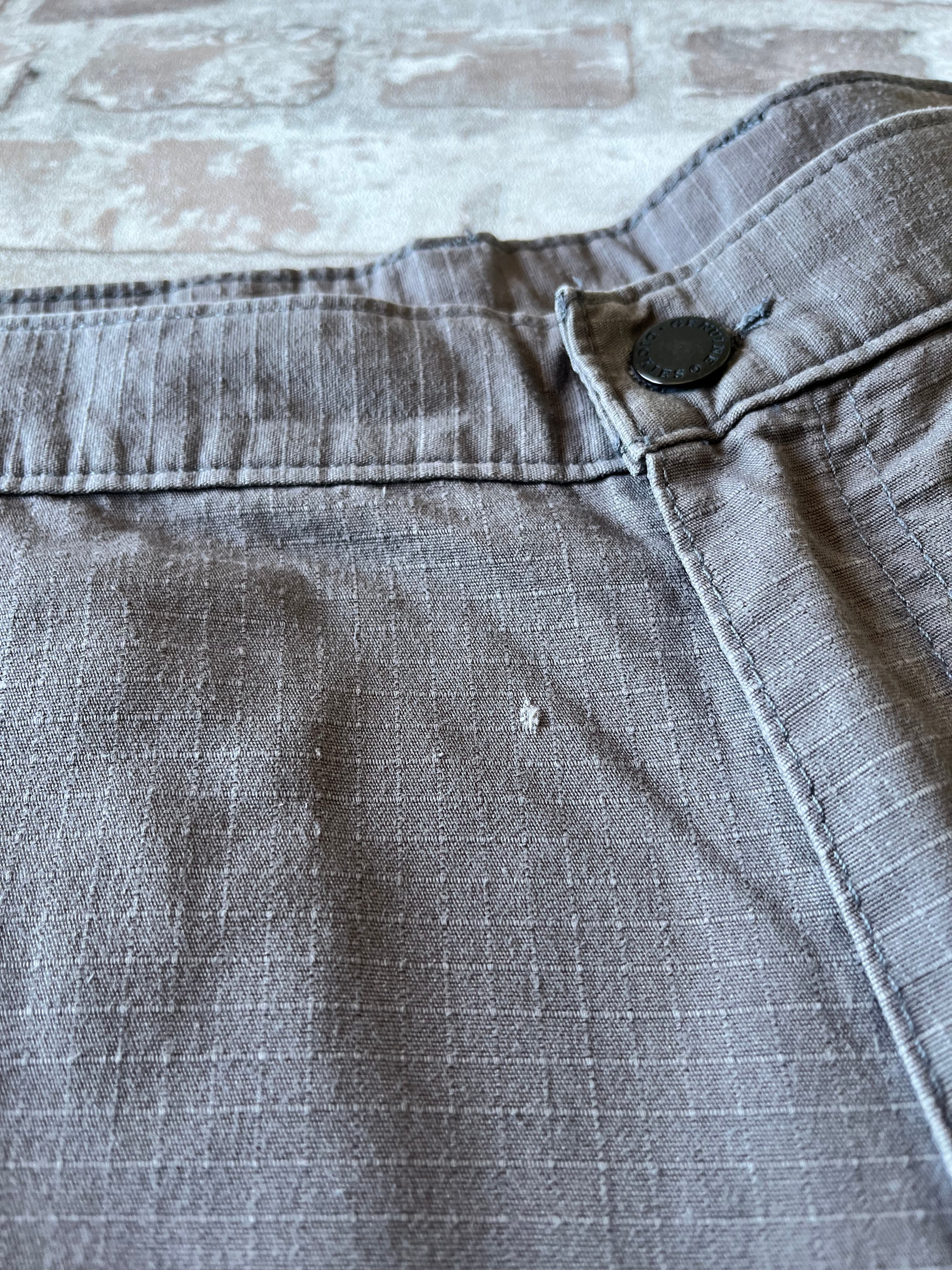 Gros plan sur un petit accroc de la toile patiné d'un short Dickies gris de seconde main