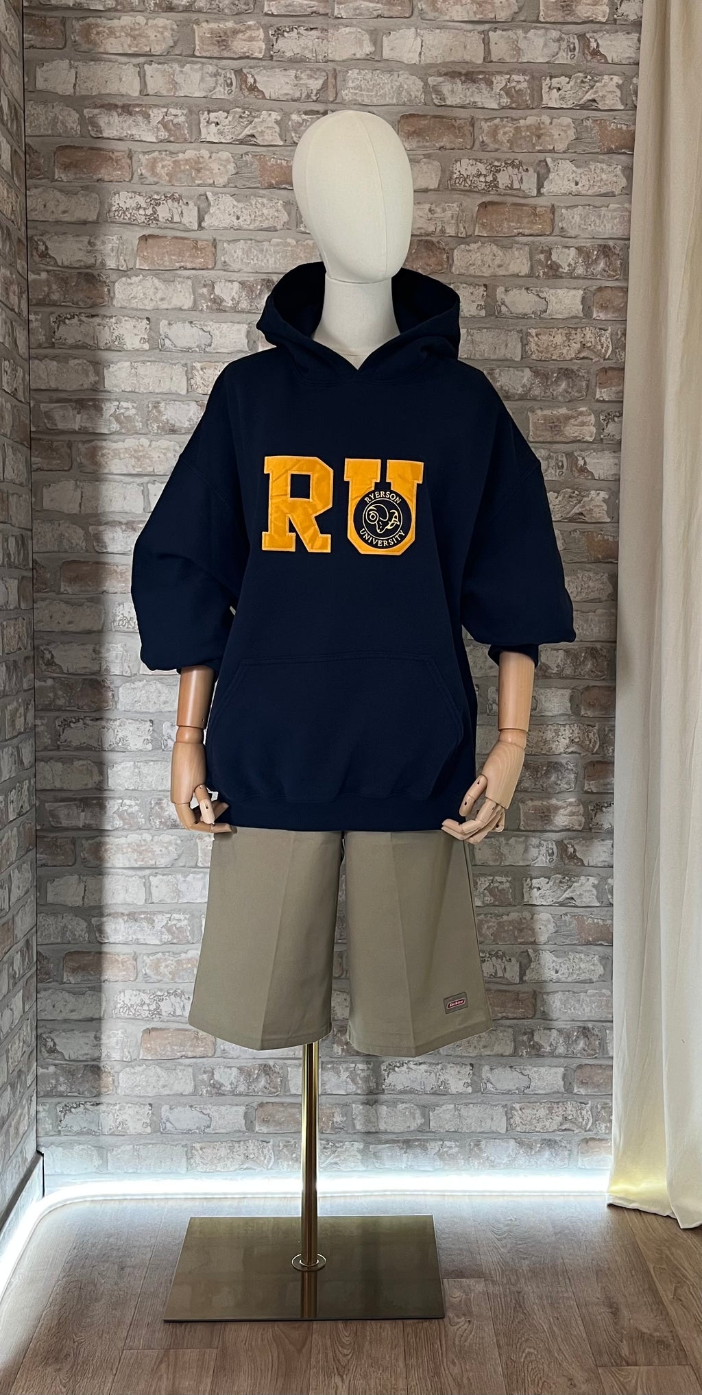 Hoodie vintage bleu marine Ryerson University à lettrage jaune porté avec un bermuda Dickies beige style skater des années 2000.
