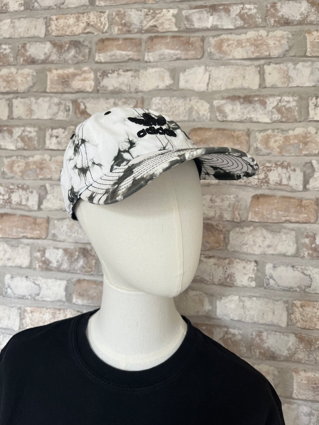 Casquette dad hat Adidas Originals au motif tie-dye marbré noir et blanc avec logo trèfle brodé, présentée sur mannequin.