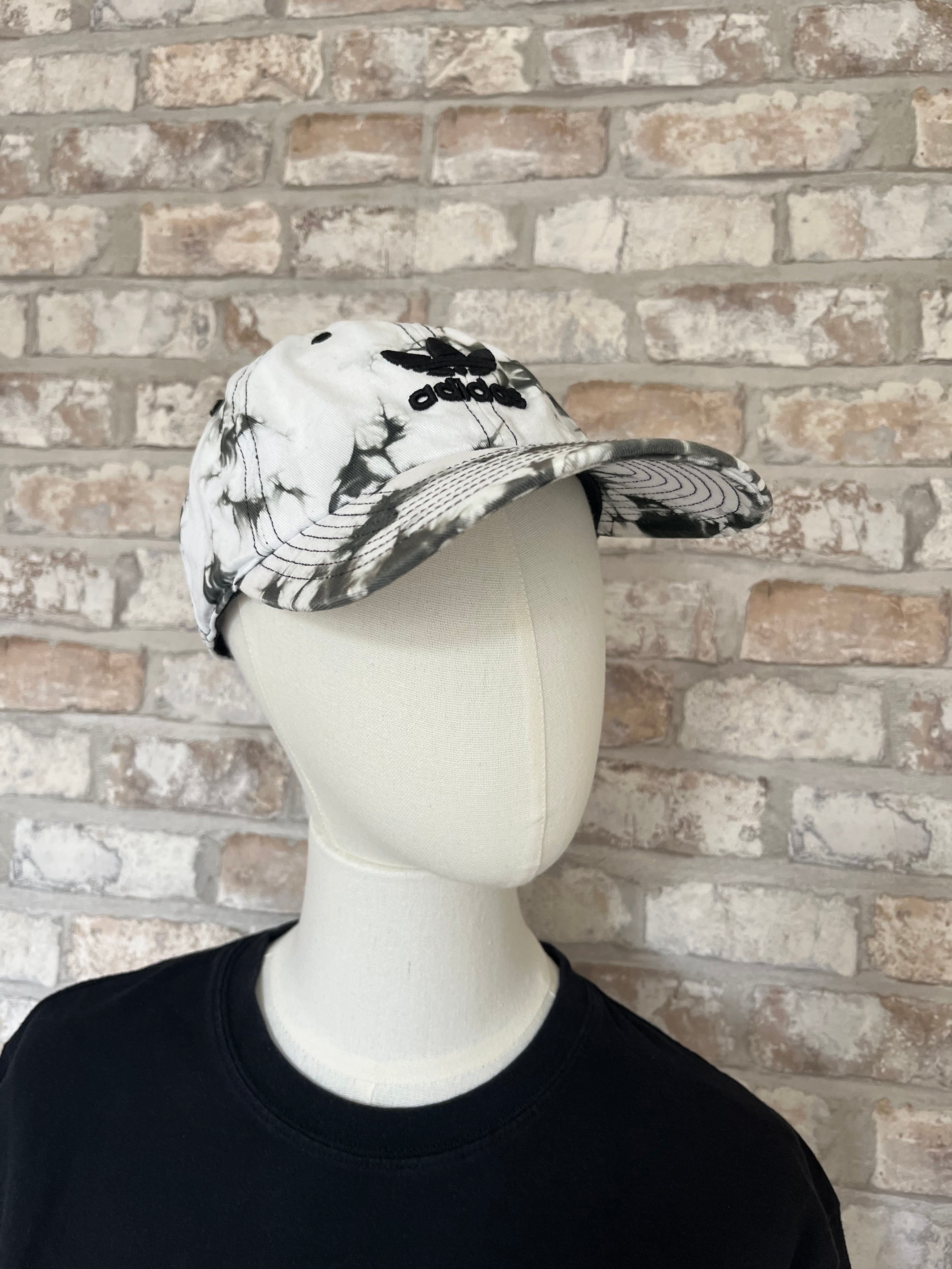 Casquette dad hat Adidas Originals au motif tie-dye marbré noir et blanc avec logo trèfle brodé, présentée sur mannequin.