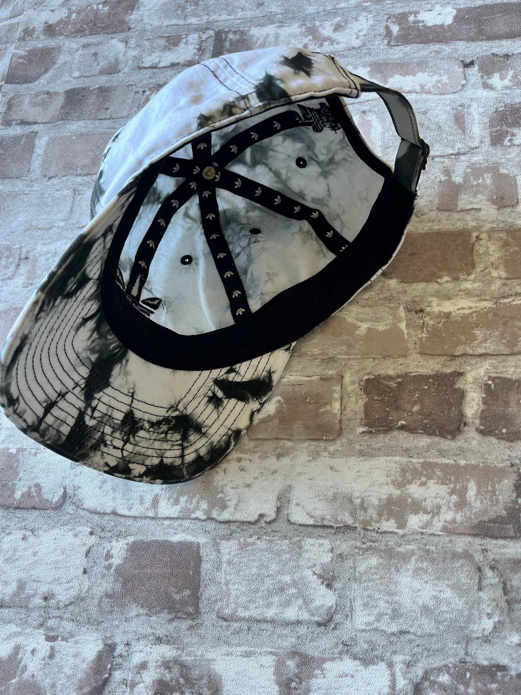 Casquette dad hat Adidas Originals au motif tie-dye marbré noir et blanc avec logo trèfle brodé, présentée à plat, vue intérieure