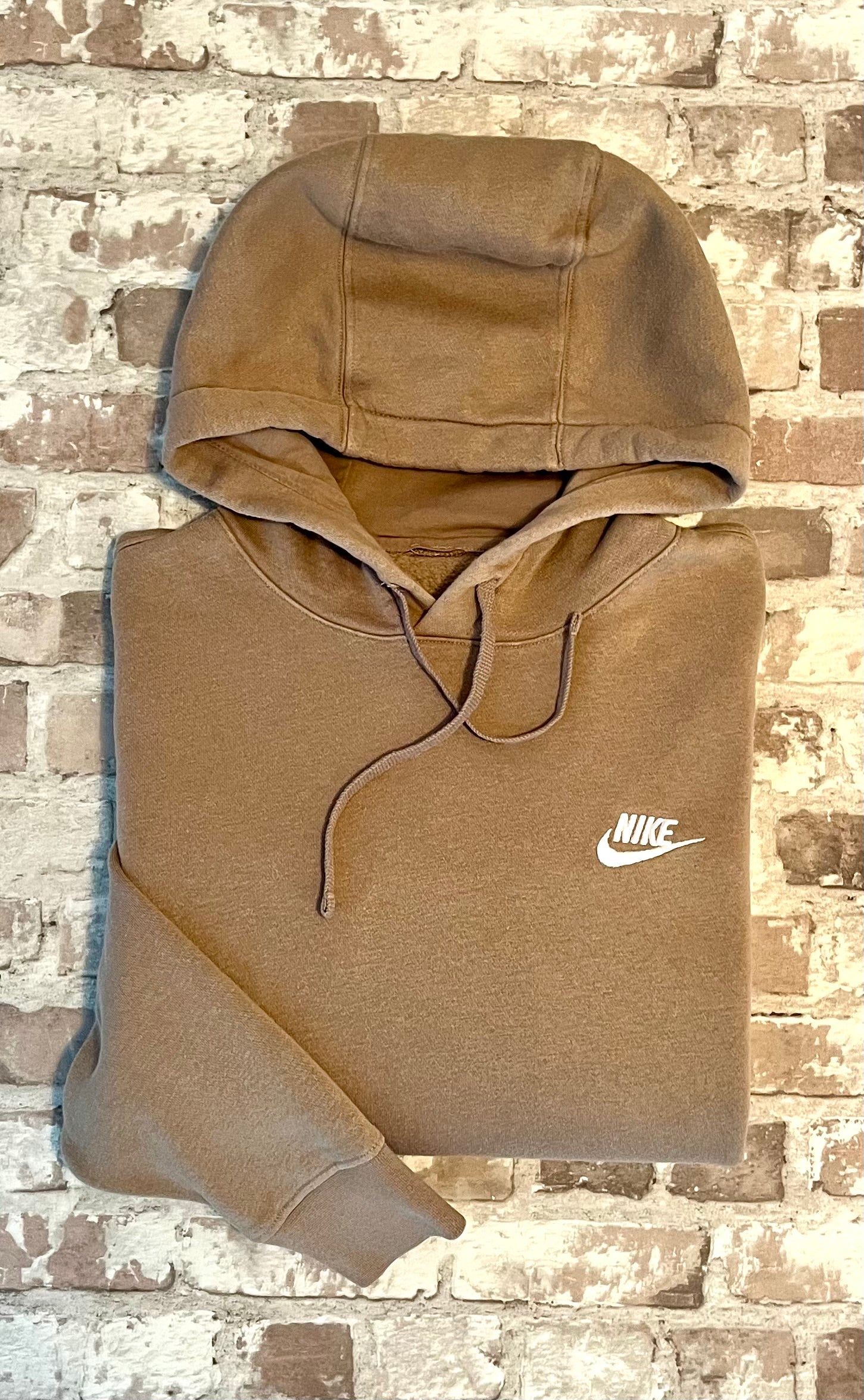 Sweat à capuche Nike Club Fleece couleur beige sable clair avec logo Futura brodé sur la poitrine, présenté plié à plat, plié