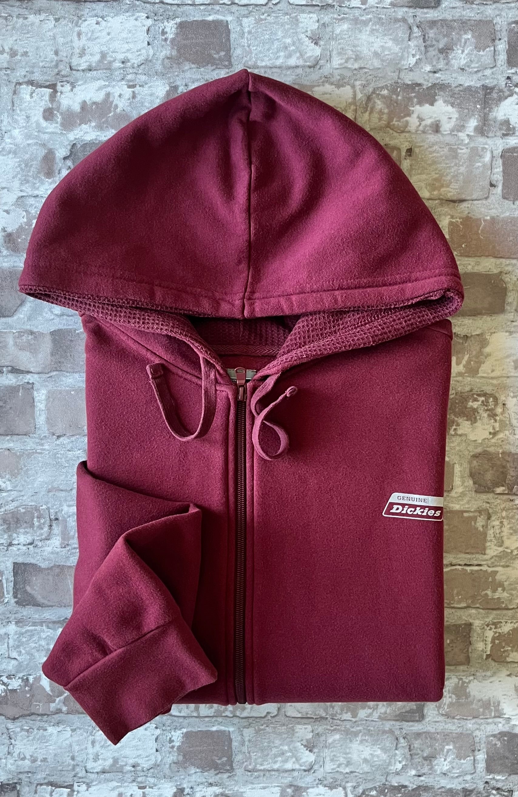 Sweat à capuche zippé vintage Genuine Dickies couleur bordeaux maroon avec logo poitrine et étiquette de la marque sur la poche, présenté à plat, plié