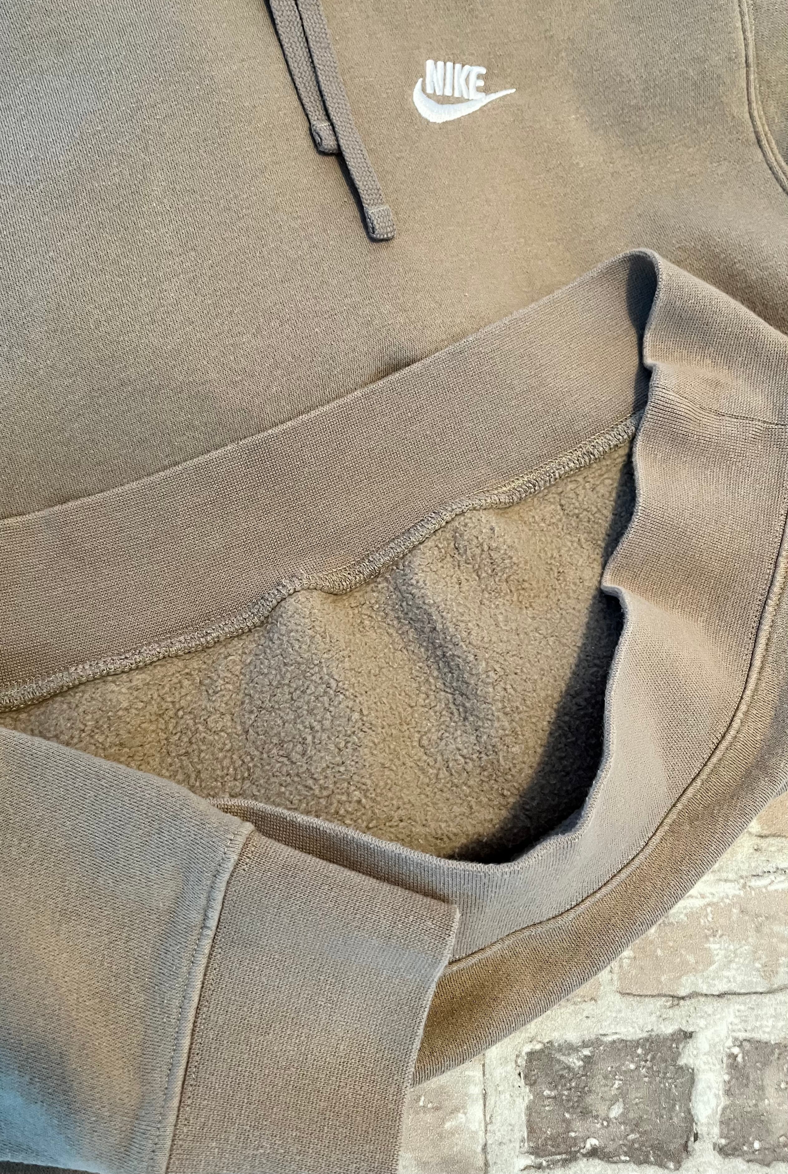 Sweat à capuche Nike Club Fleece couleur beige sable clair avec logo Futura brodé sur la poitrine, présenté plié à plat. Focus Doublure