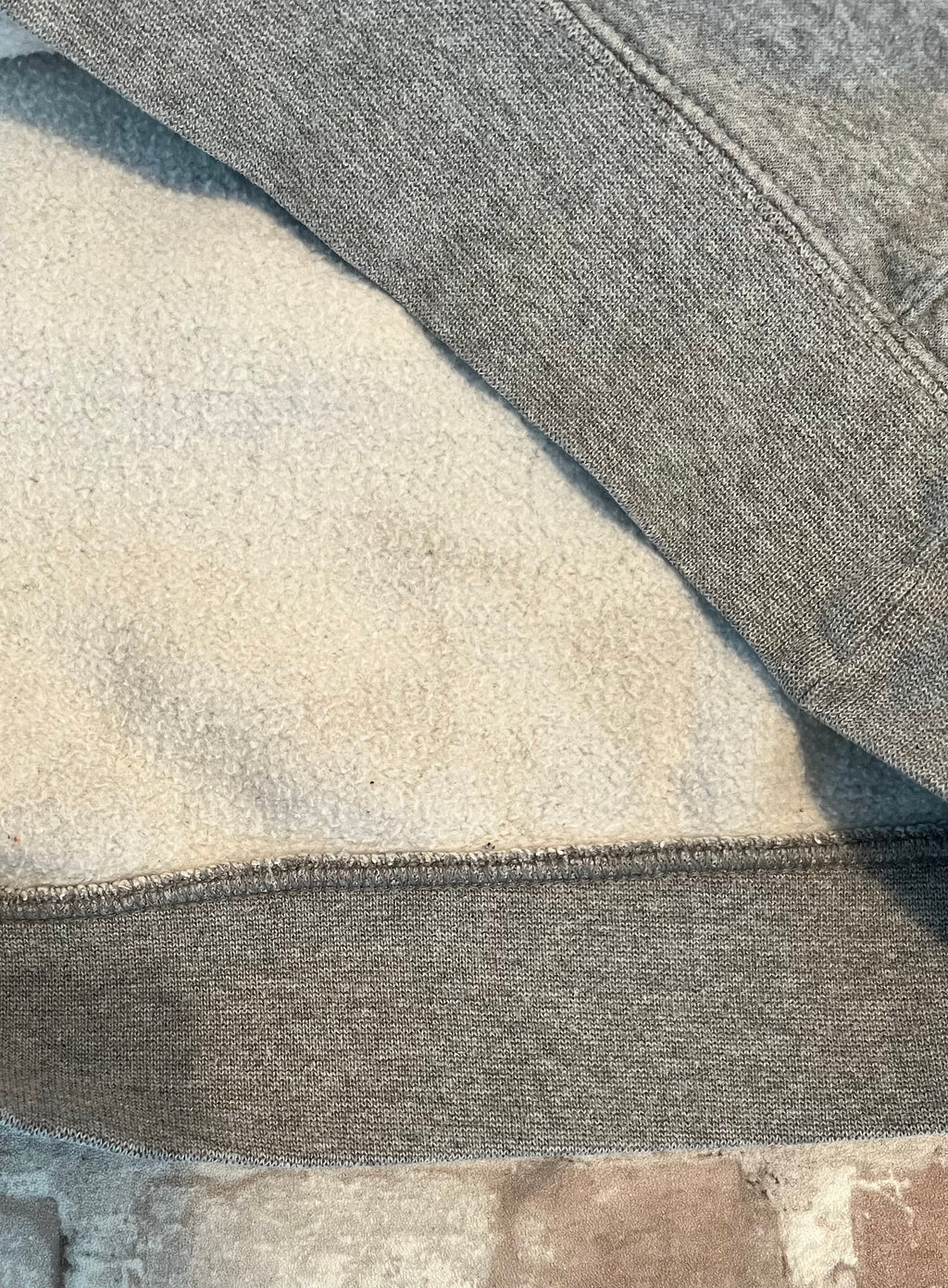 Gros plan sur les légères traces d'usage situées uniquement sur la doublure intérieure d'un hoodie en coton gris Nike.