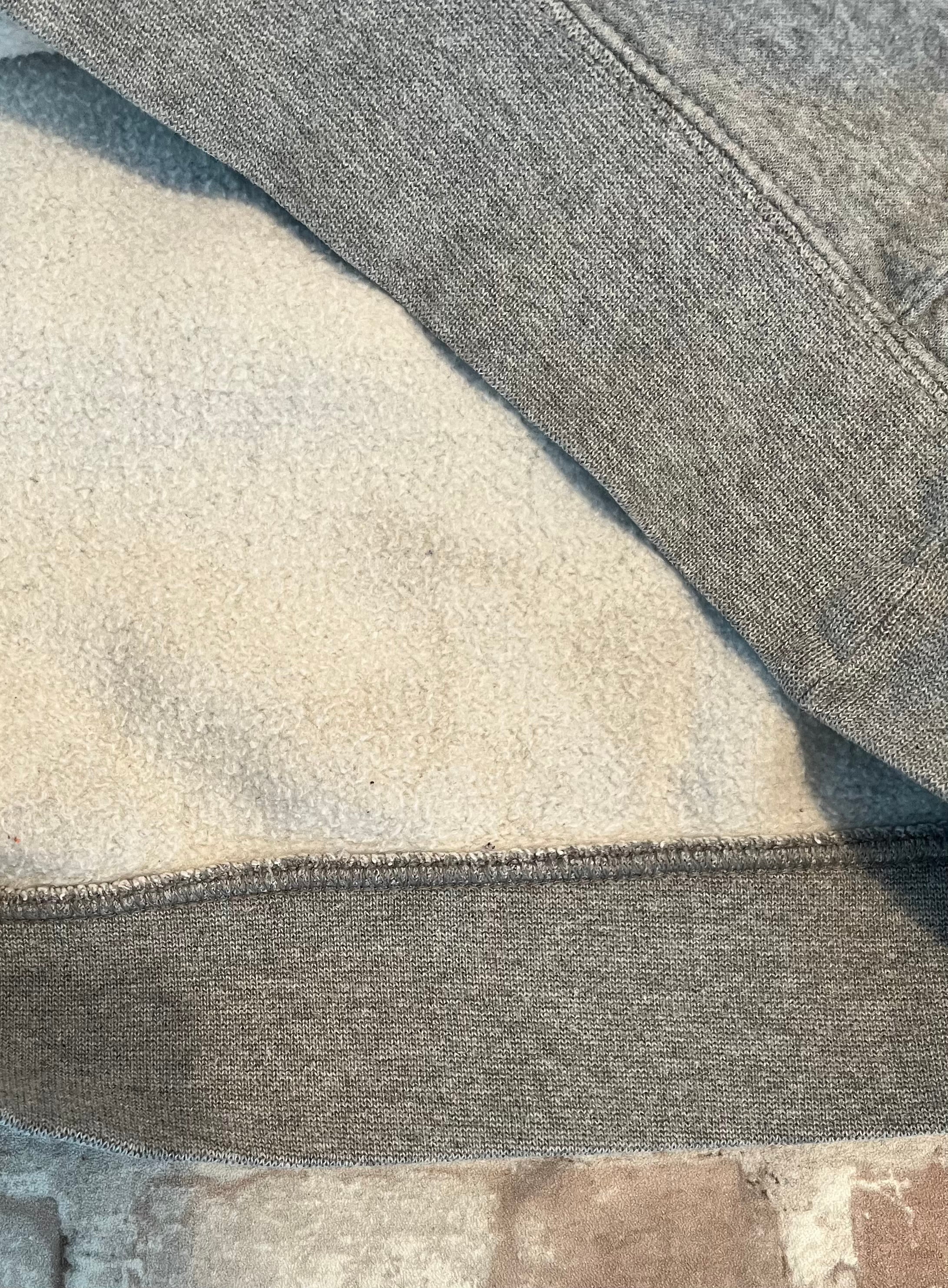 Gros plan sur les légères traces d'usage situées uniquement sur la doublure intérieure d'un hoodie en coton gris Nike.