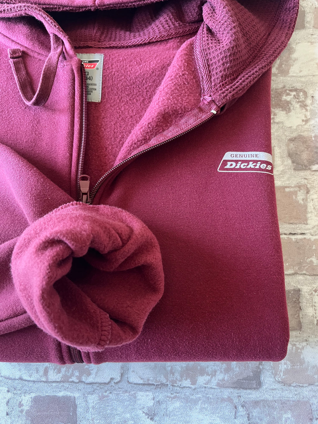Sweat à capuche zippé vintage Genuine Dickies couleur bordeaux maroon avec logo poitrine et étiquette de la marque sur la poche, présenté à plat, plié , focus doublure