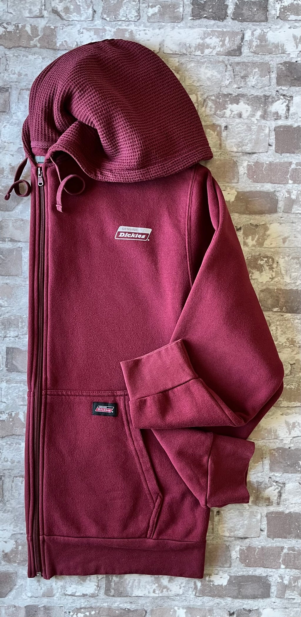 Sweat à capuche zippé vintage Genuine Dickies couleur bordeaux maroon avec logo poitrine et étiquette de la marque sur la poche, présenté à plat, de profil