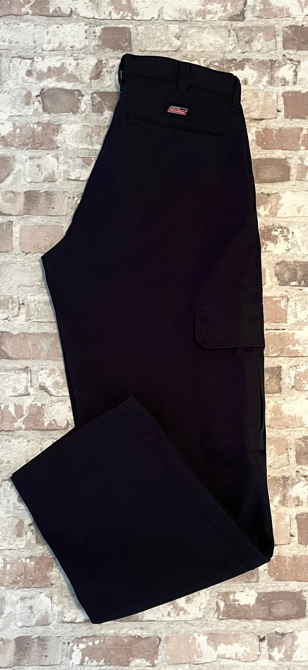 Pantalon cargo Dickies droit noir avec poches latérales à rabats velcro et pli permanent, présenté plié à plat.