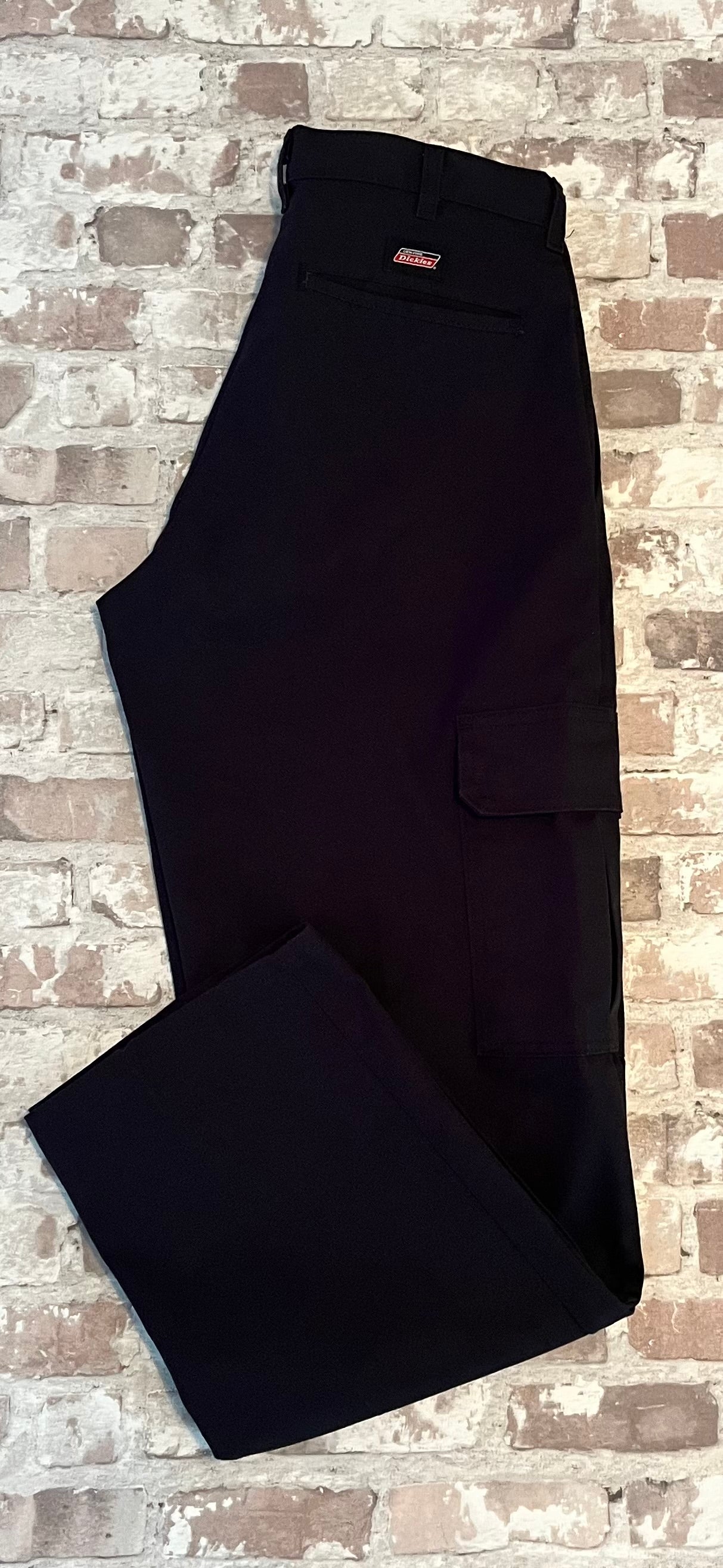 Pantalon cargo Dickies droit noir avec poches latérales à rabats velcro et pli permanent, présenté plié à plat.