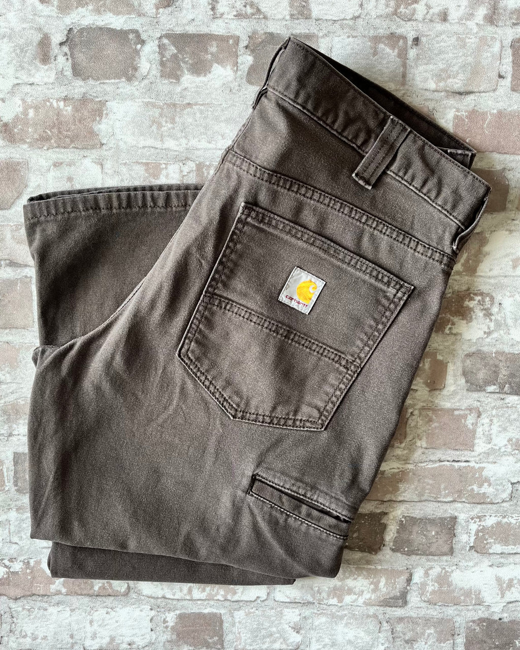 Pantalon en coton stretch marron foncé Carhartt Rugged Flex avec poches outils latérales, présenté à plat, plié