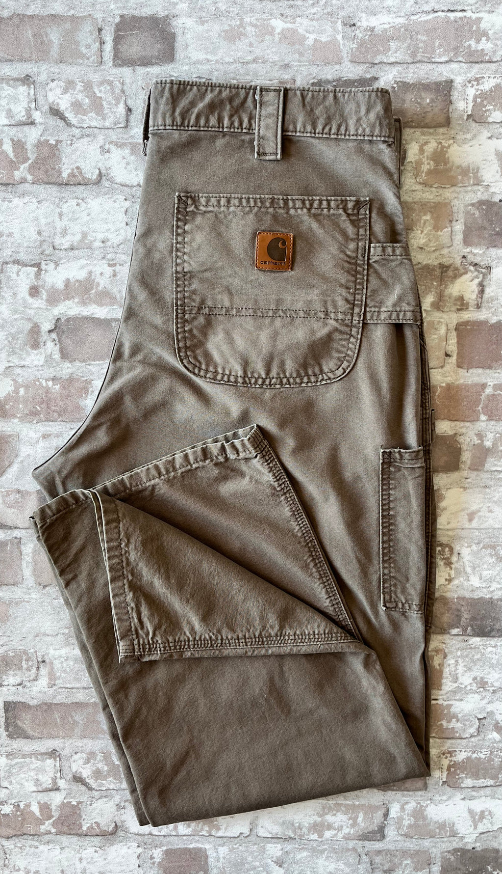 Pantalon de menuisier marron clair Carhartt B151 plié à plat, mettant en avant la toile en coton canvas et le patch en cuir