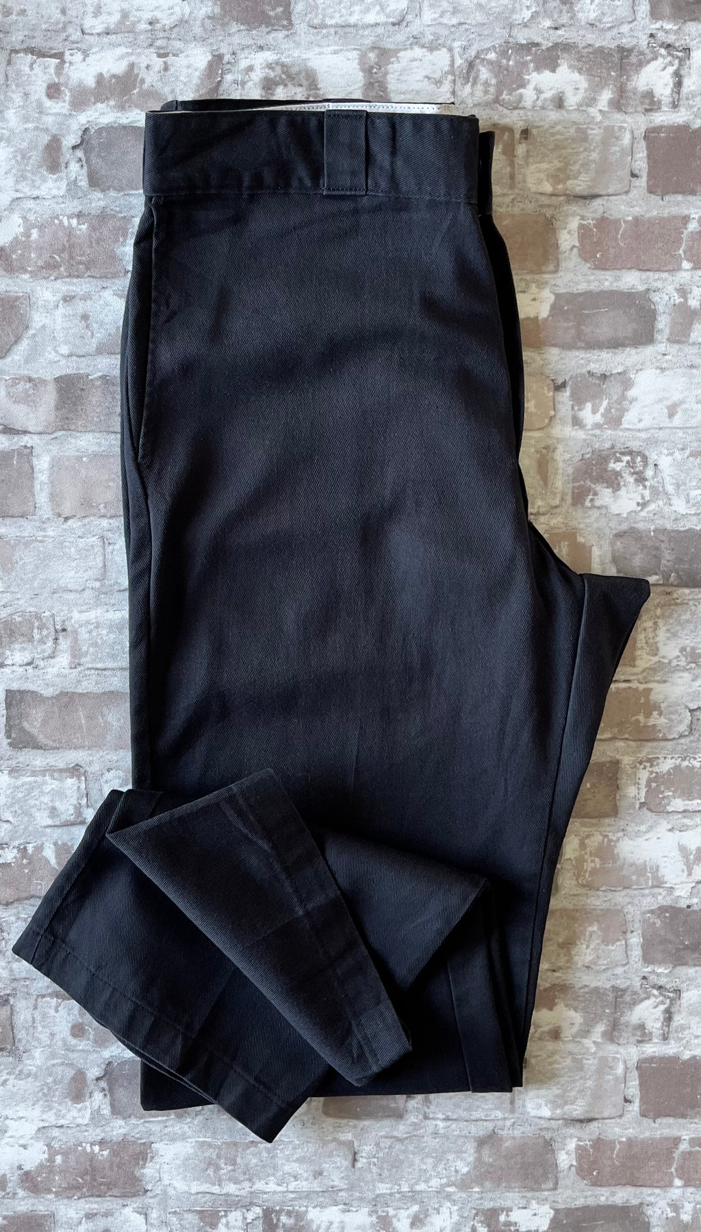Pantalon de travail vintage Dickies 874 Original Fit noir délavé avec le patch logo Ox Collar à l'arrière, présenté plié à plat.