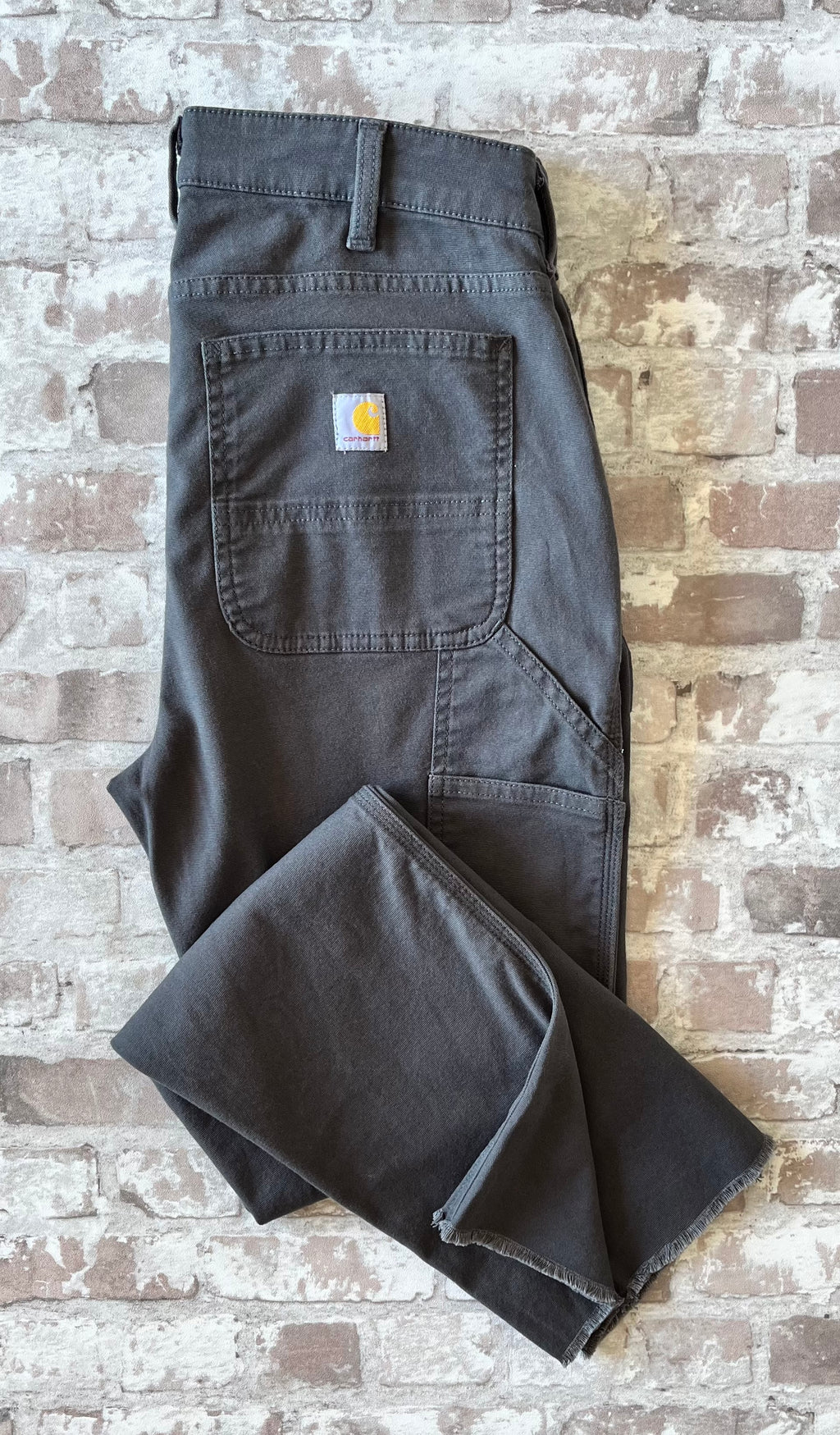 Pantalon de travail gris anthracite femme Carhartt Carpenter avec bas de jambes coupés à cru, présenté à plat 
