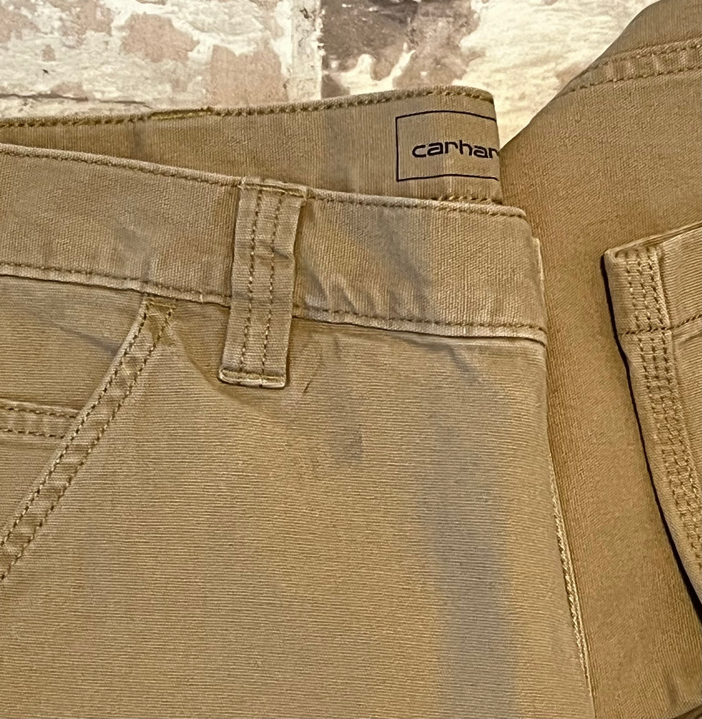 Gros plan sur les légères marques d'usage sun un pantalon Carhartt beige.