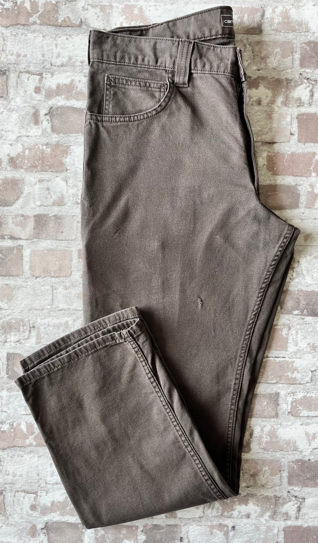 Pantalon en coton stretch marron foncé Carhartt Rugged Flex avec poches outils latérales, présenté à plat de face, accroc visible