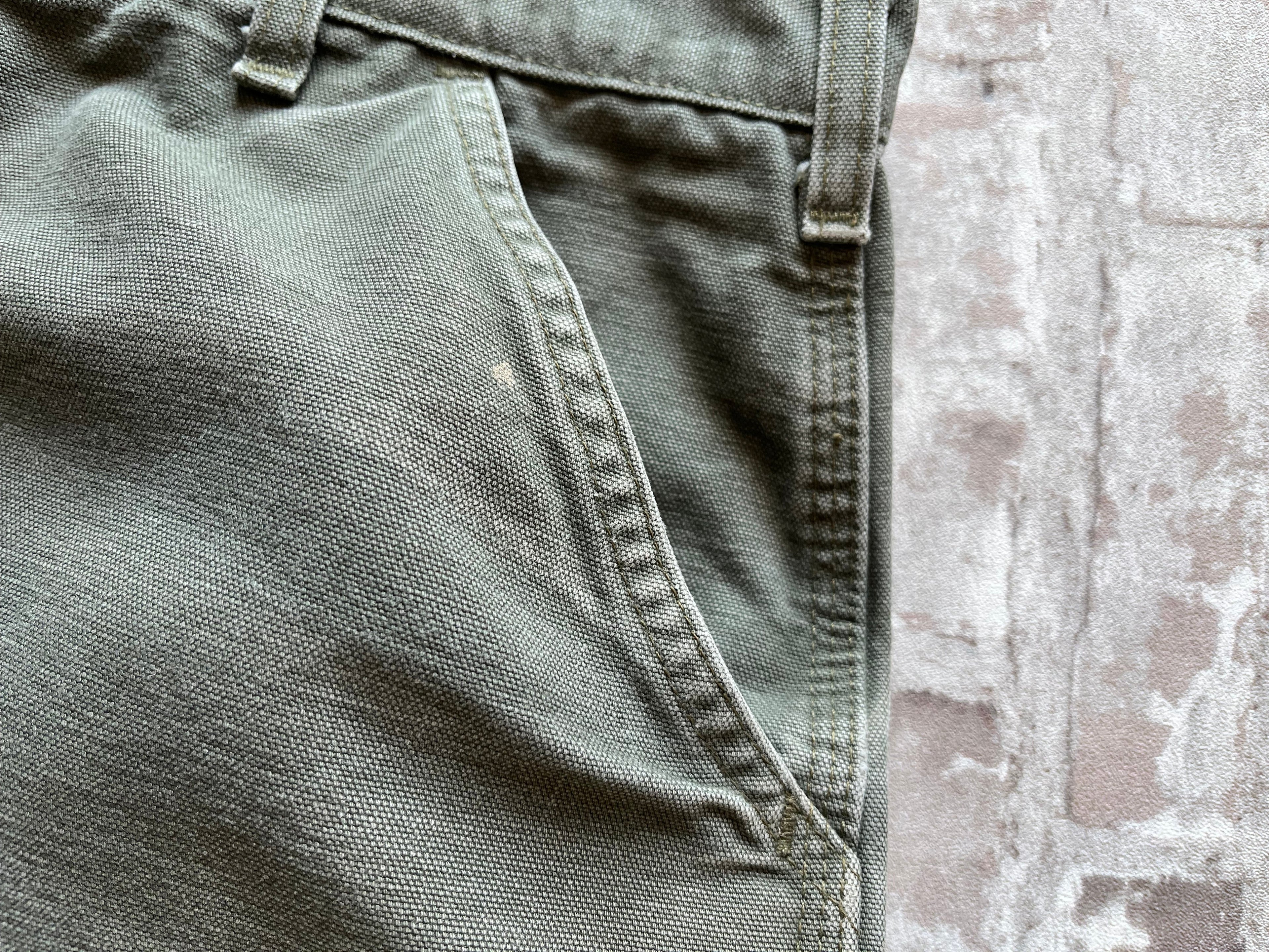 Gros plan sur les usures naturelles et petite tache sur la toile en coton épais d'un pantalon Carhartt de seconde main.