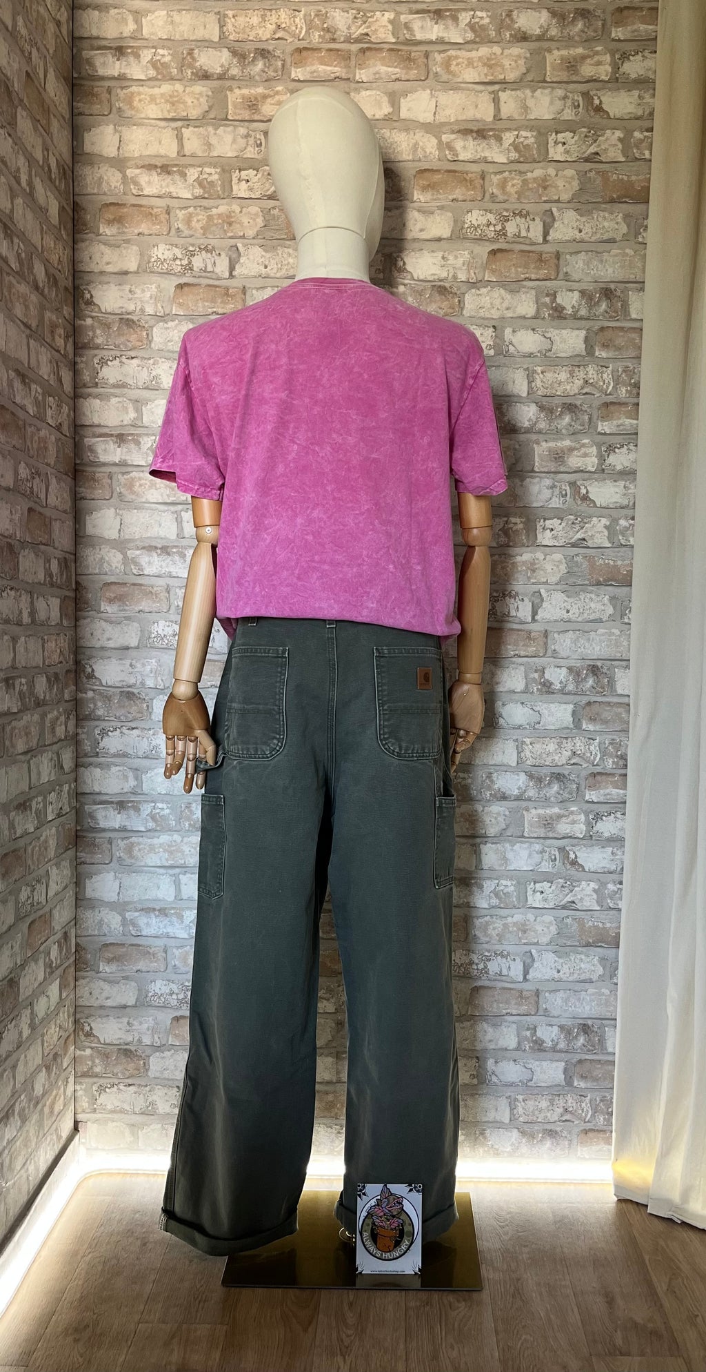 Pantalon Carpenter Carhartt B11 , MOS Kaki Faded , sur mannequin de dos un t-shirt Nirvana rose acid wash et un patch La Barbuda posés au sol