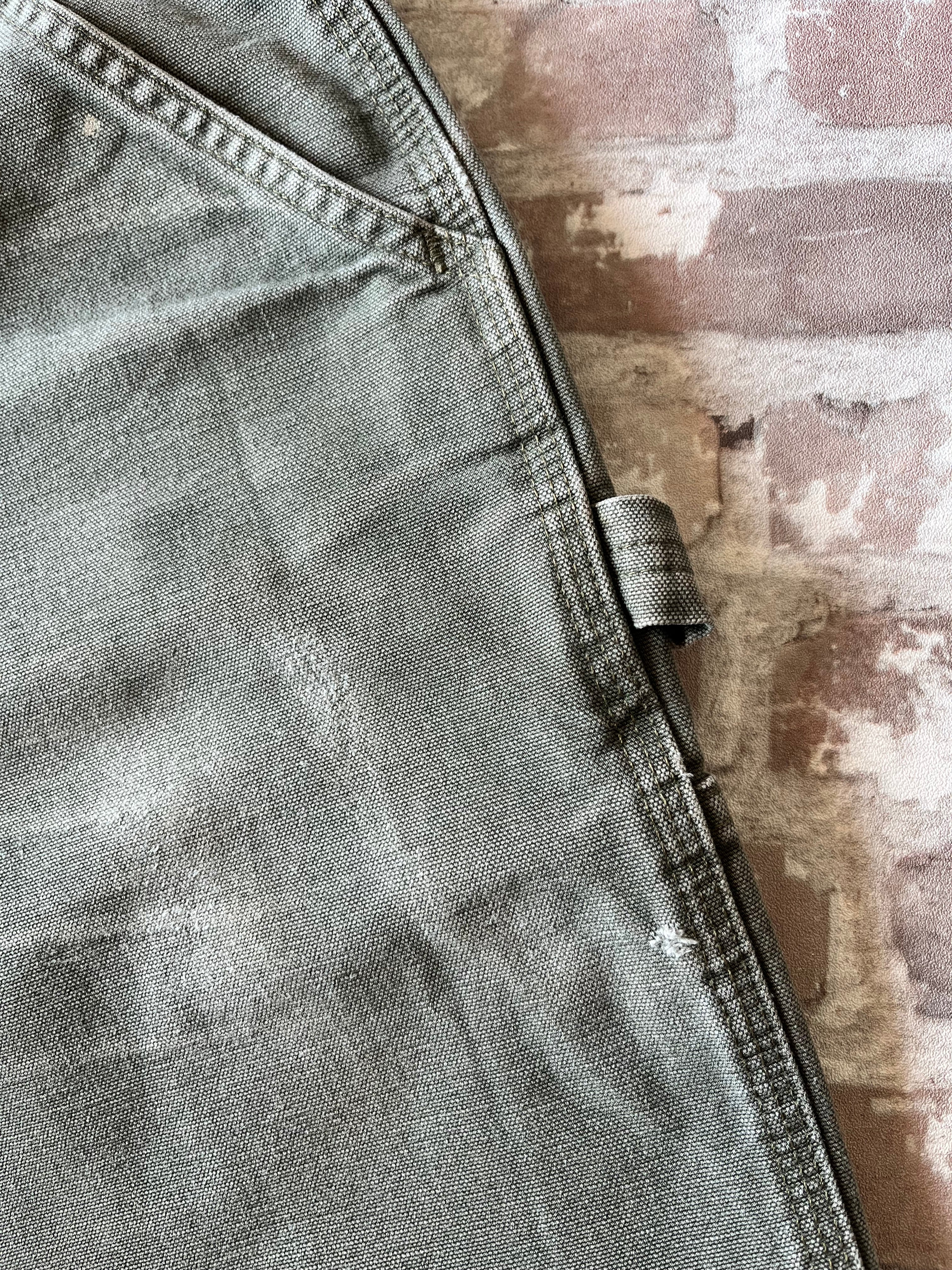 Gros plan sur les usures naturelles et petits accrocs sur la toile en coton épais d'un pantalon Carhartt de seconde main.