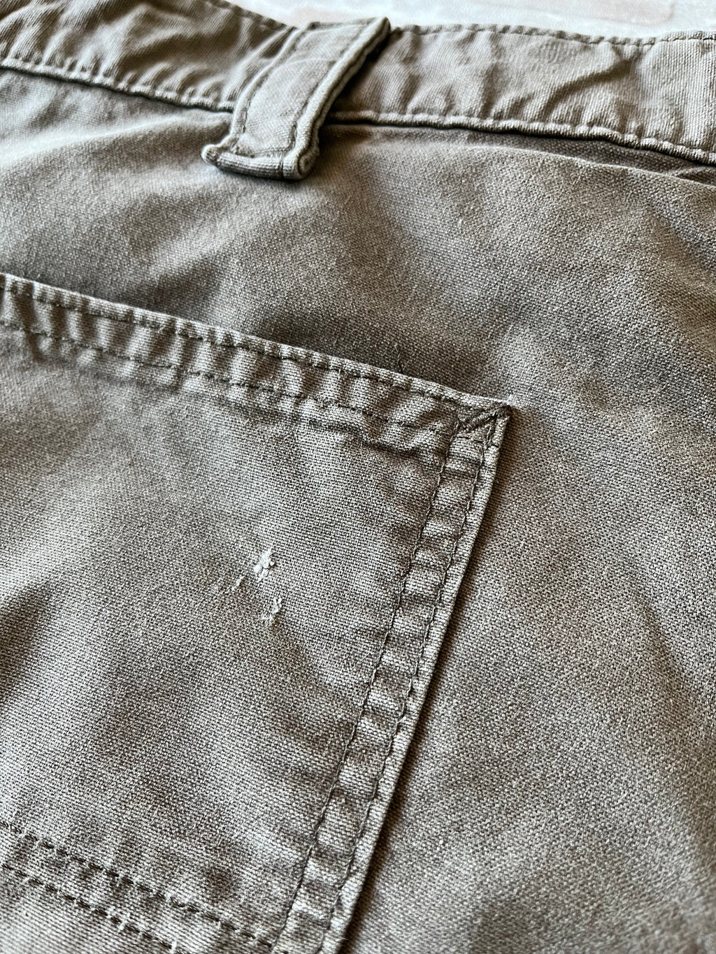 Gros plan sur de légères marques d'usage et petits accrocs authentiques sur la toile en coton d'un pantalon Carhartt.