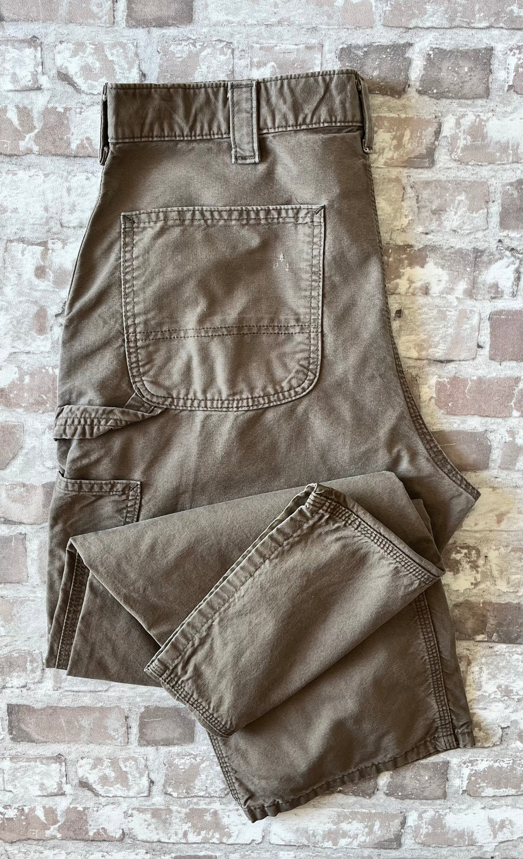 Pantalon de menuisier marron clair Carhartt B151 plié à plat, mettant en avant la toile en coton canvas et la boucle marteau.