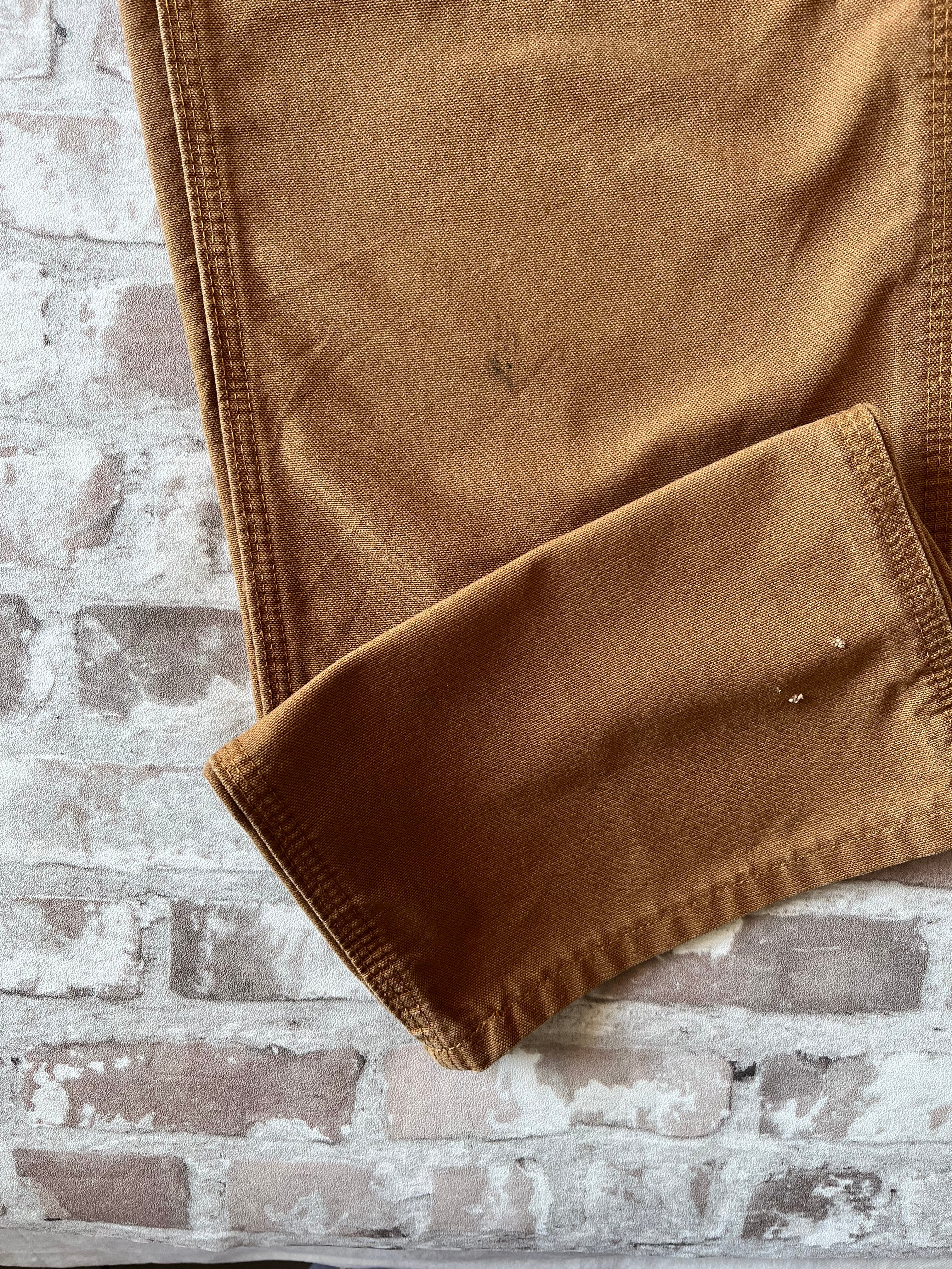 Gros plan sur des micro-accrocs sur un pantalon Carhartt marron.