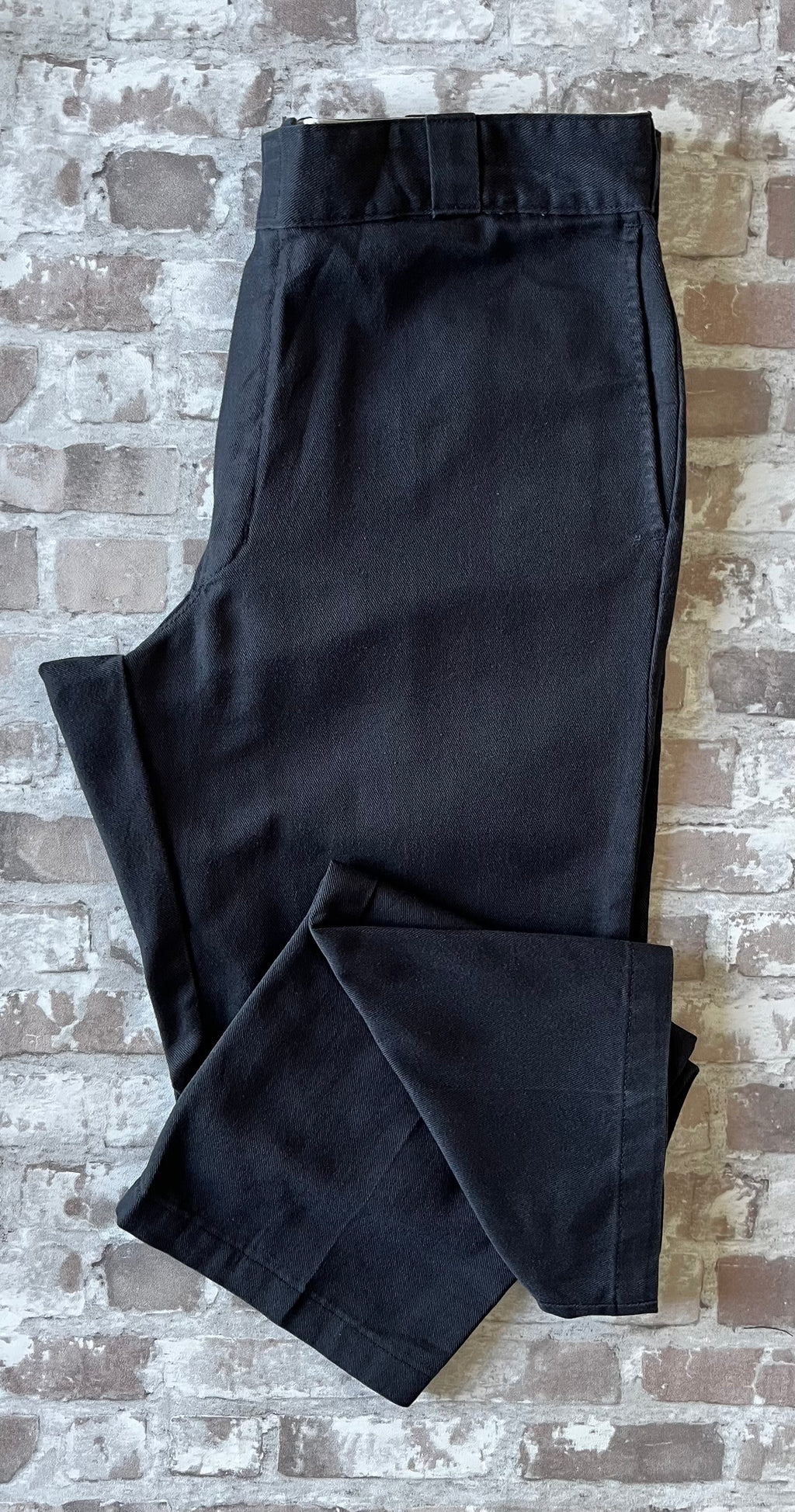 Pantalon de travail vintage Dickies 874 Original Fit noir délavé avec le patch logo Ox Collar à l'arrière, présenté plié à plat.