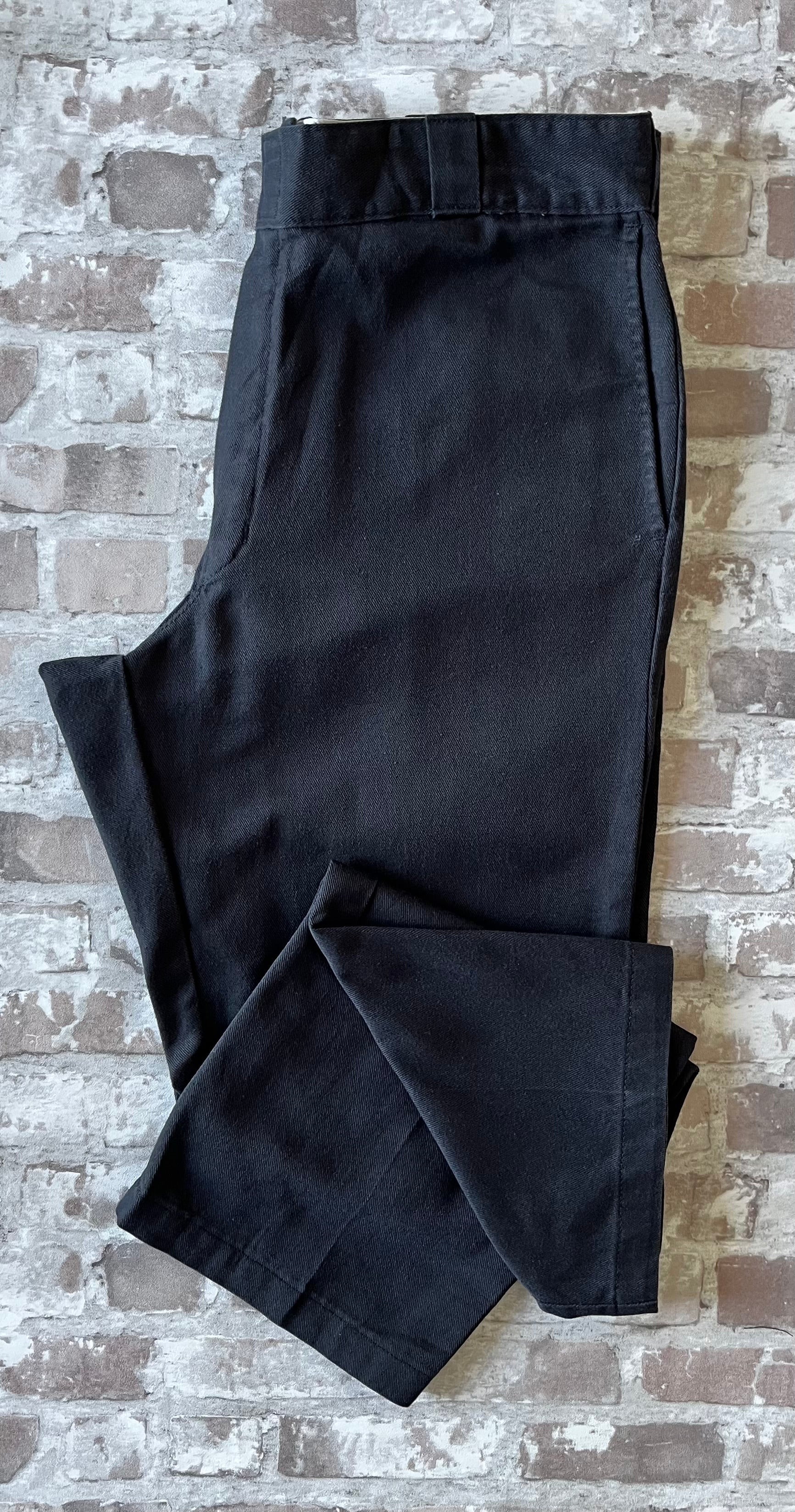 Pantalon de travail vintage Dickies 874 Original Fit noir délavé avec le patch logo Ox Collar à l'arrière, présenté plié à plat.
