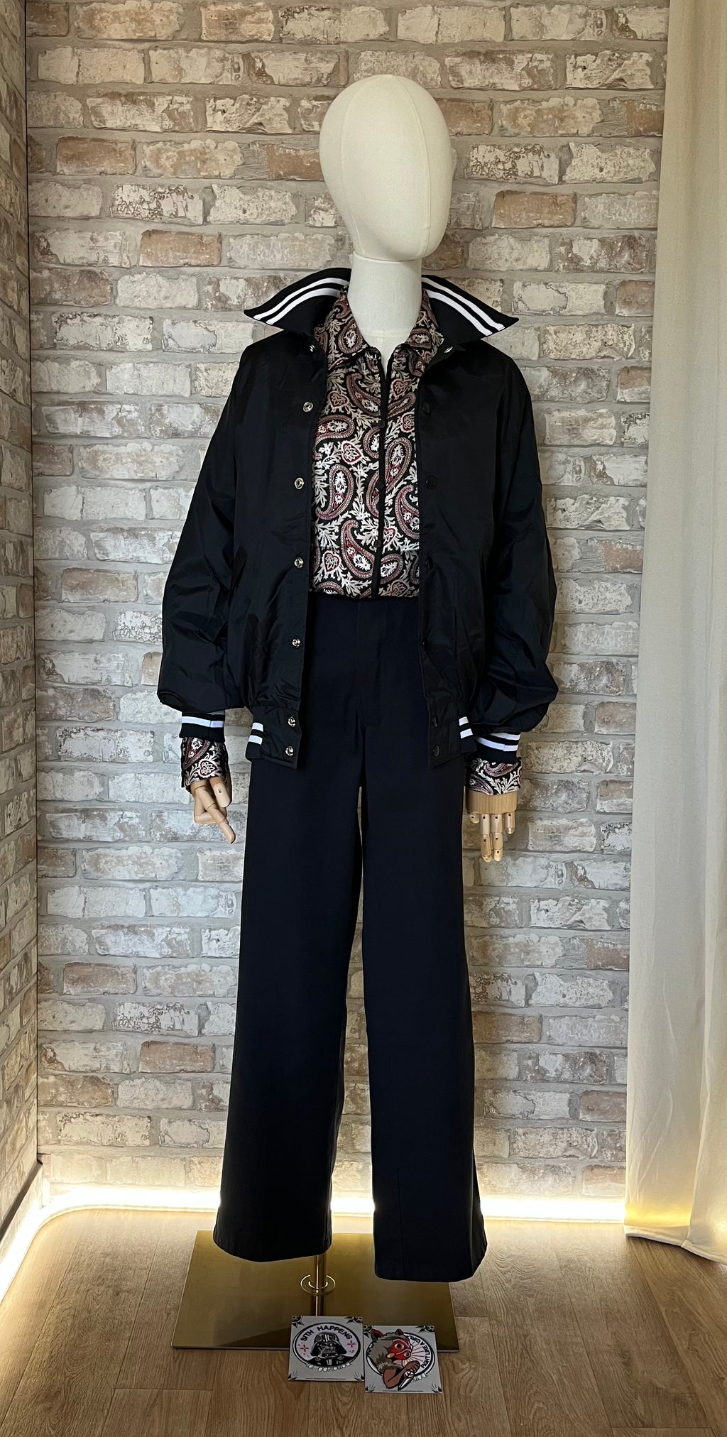 Pantalon noir Dickies 874 porté par un mannequin avec une chemise Covington rouge à motifs paisley, un coupe-vent et des patchs La Barbuda