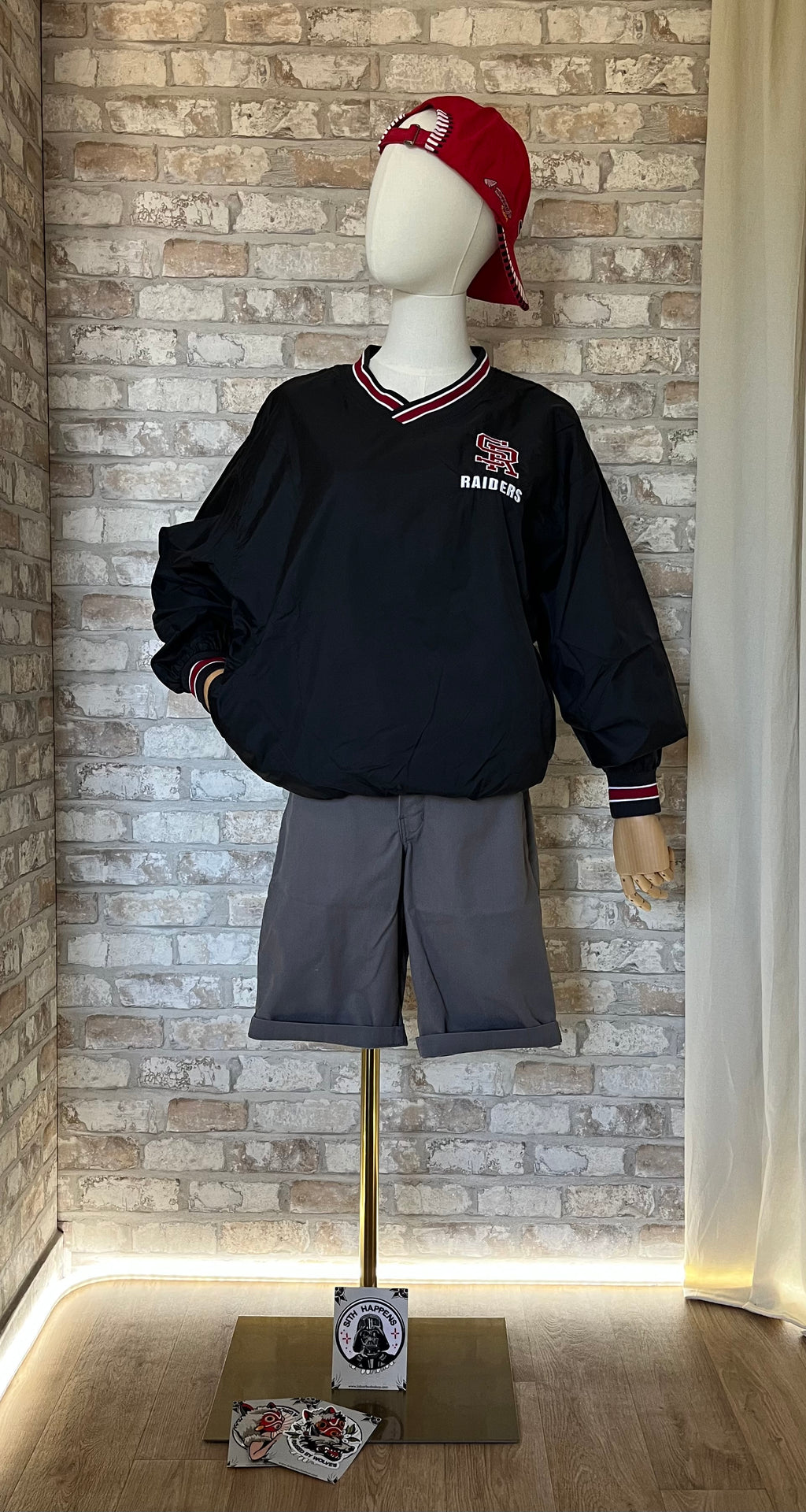 Pullover vintage noir Sport-Tek SR Raiders porté avec un short Dickies gris, une casquette rétro et un patch thermocollant La Barbuda.